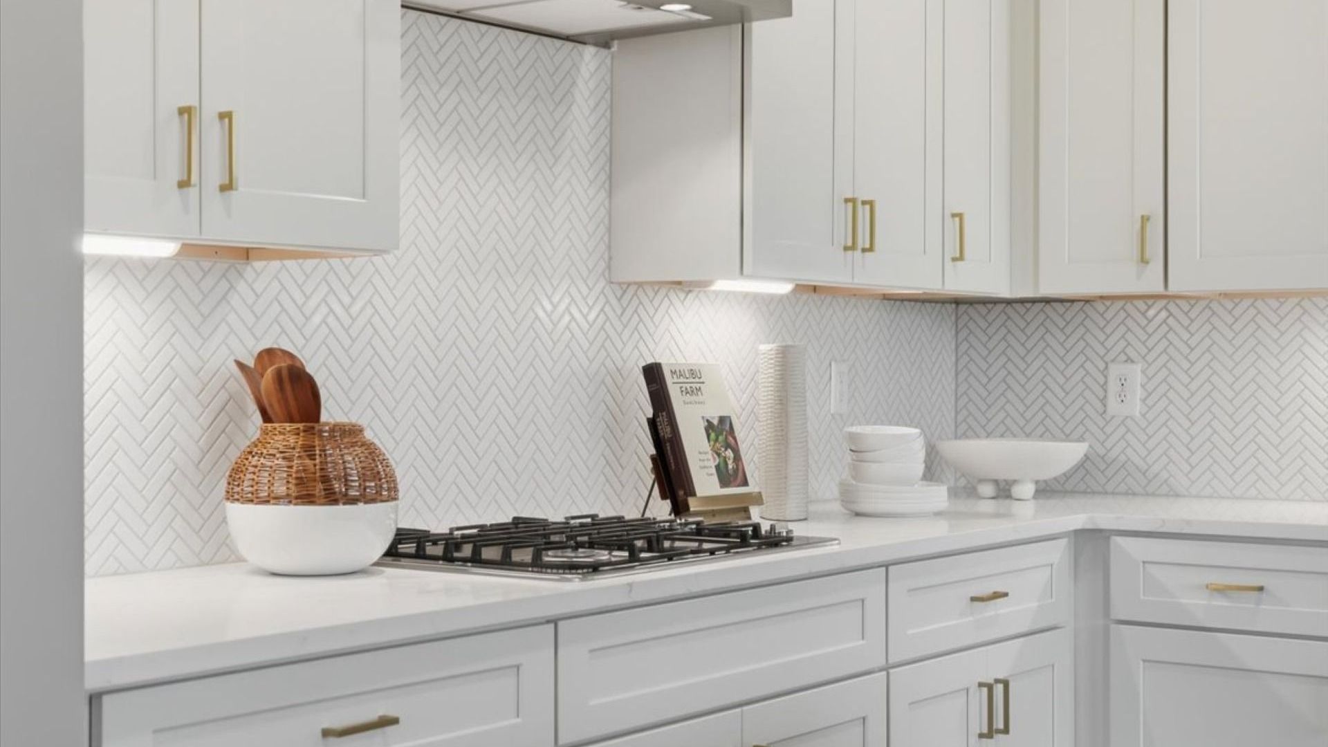 Bright modern Stonefield kitchen with white tile backsplash, white cabinetry, and gold hardware at Brighton.