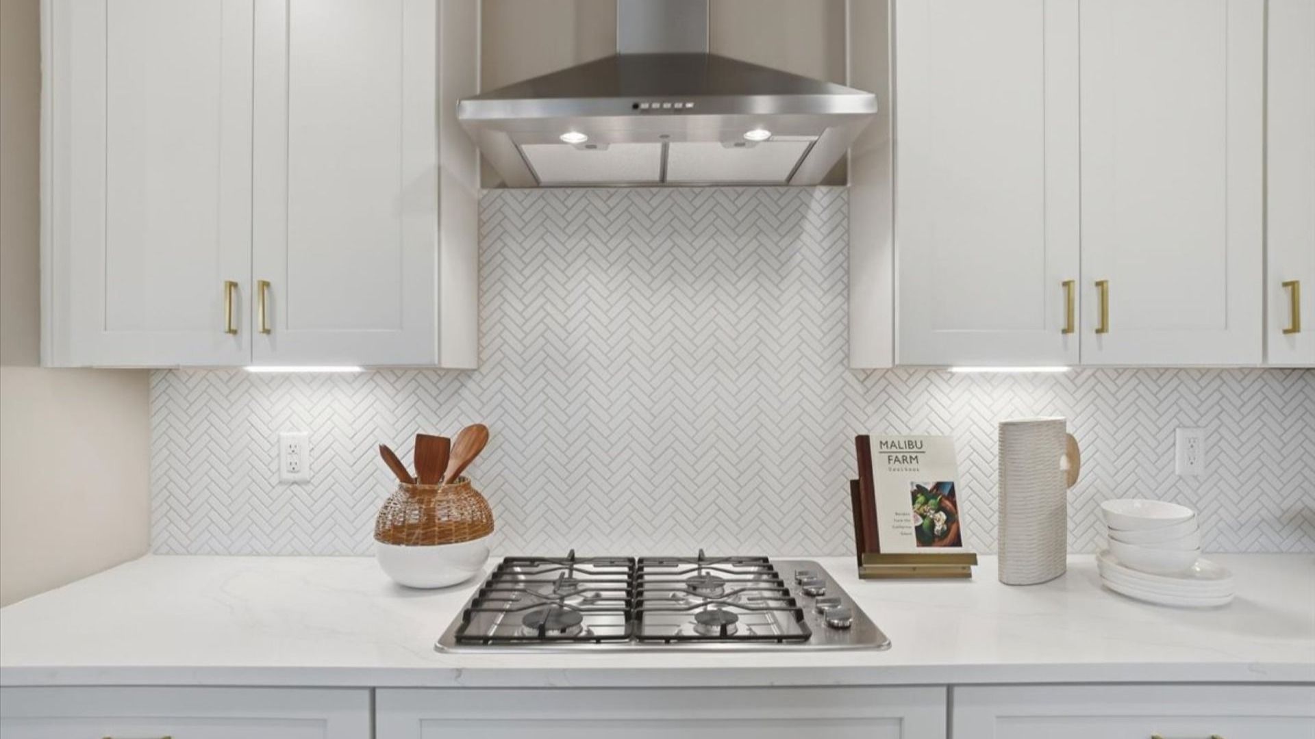 Bright modern Stonefield kitchen with white tile backsplash, white cabinetry, and gold hardware at Brighton.