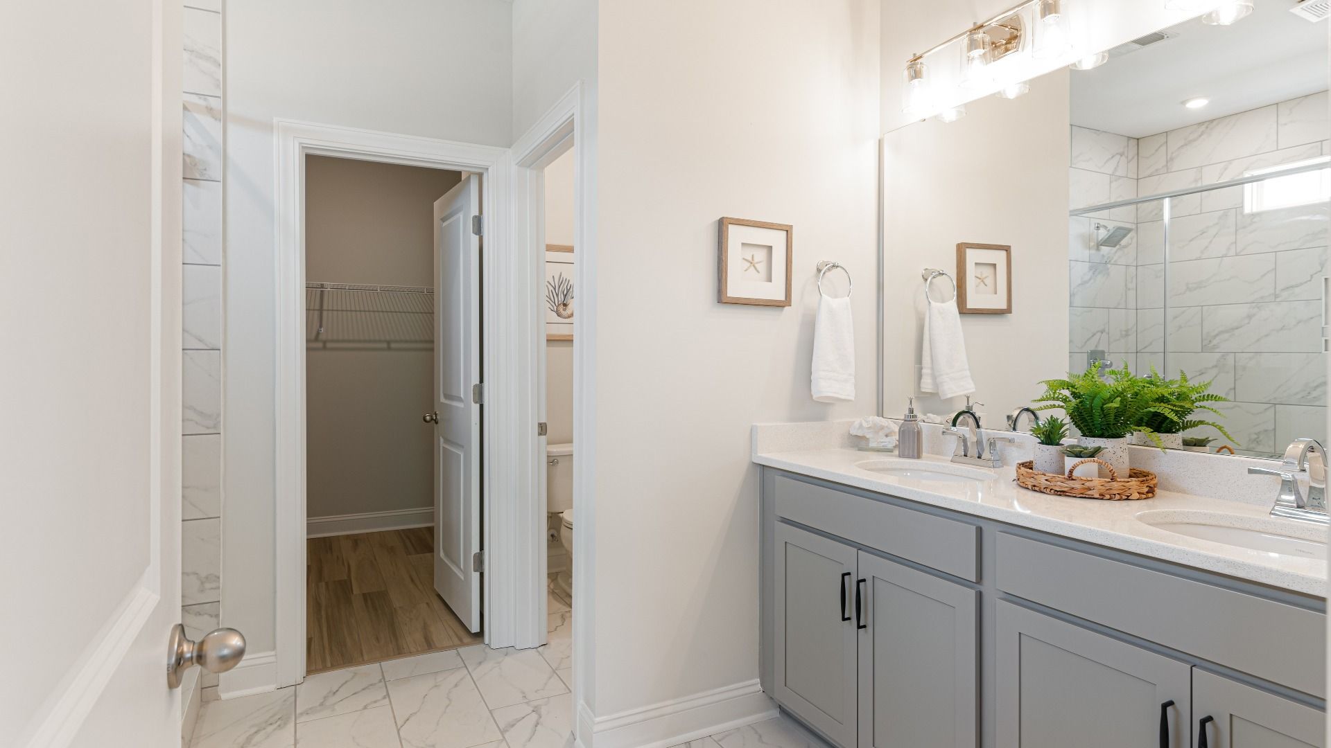 owner's suite bath with dual vanity, tile shower, and water closet