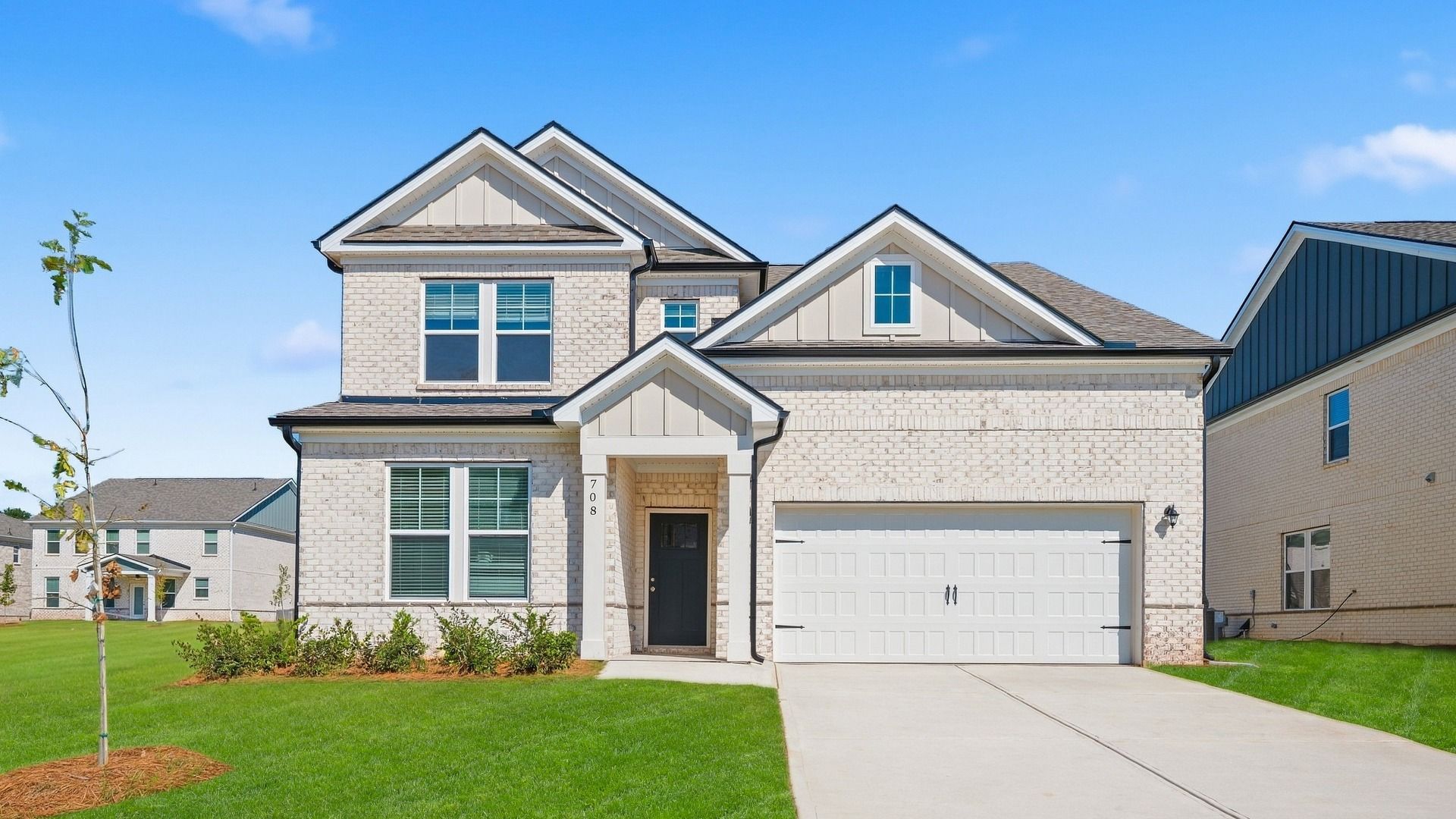Wynwood two-story home with brick exterior featuring stone and siding accents and two-car front-entry garage at Bowers Farm.
