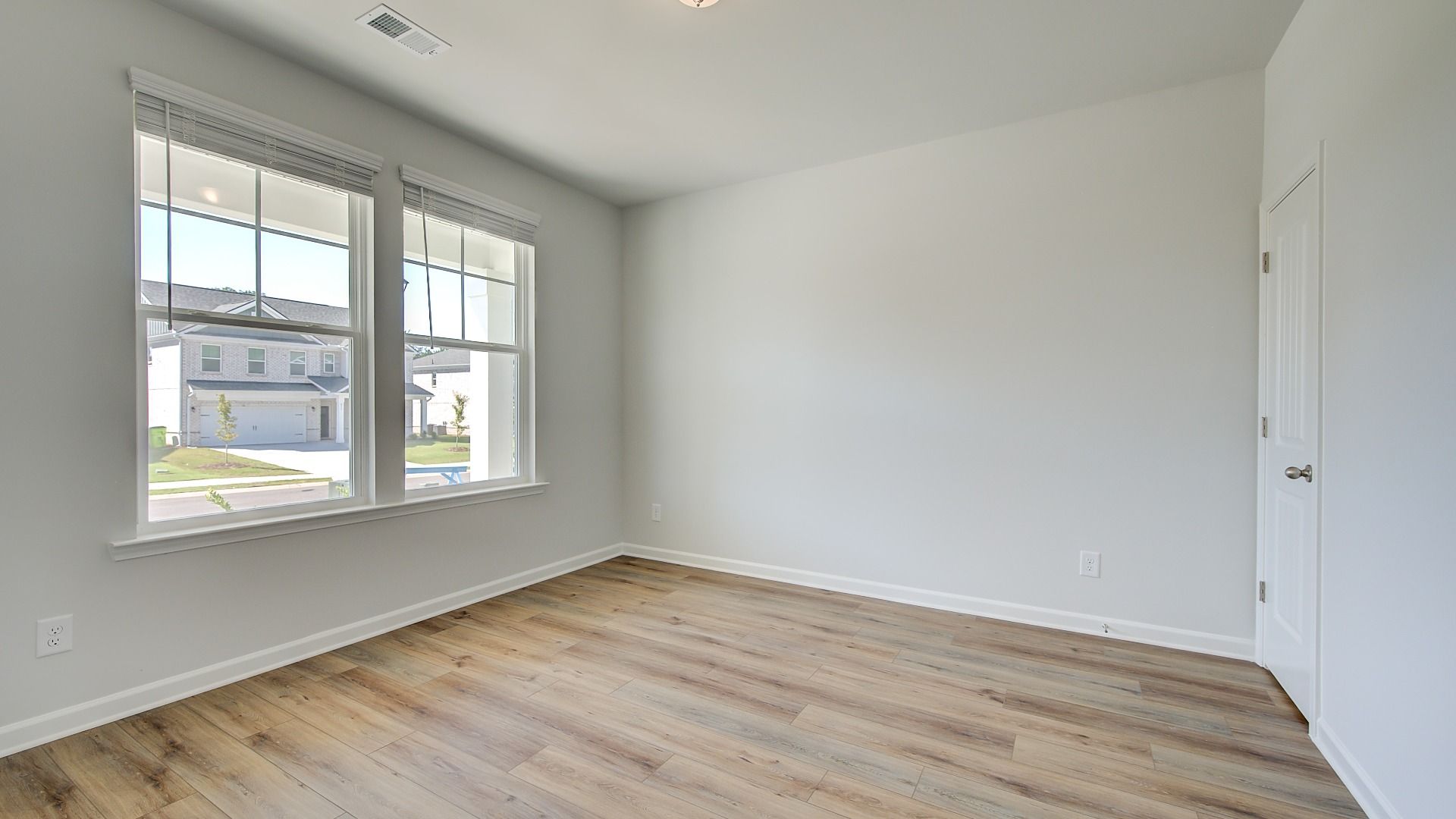 Bright first-floor guest room with natural light and LVP flooring in the Wagener at Bowers Farm in McDonough, GA.