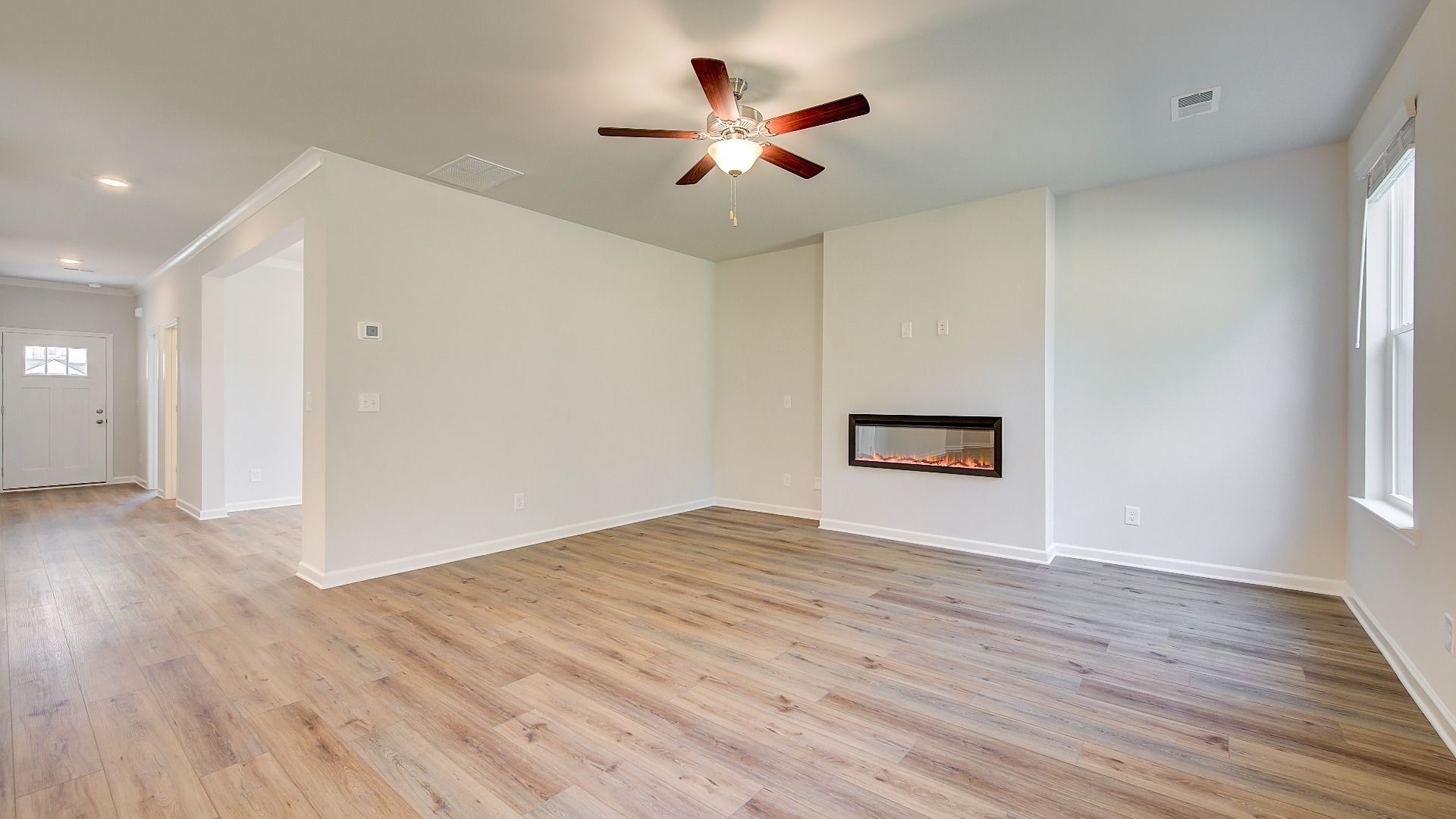 Modern family room with LVP flooring, fireplace, and natural light in the Wagener at Bowers Farm in McDonough, GA.