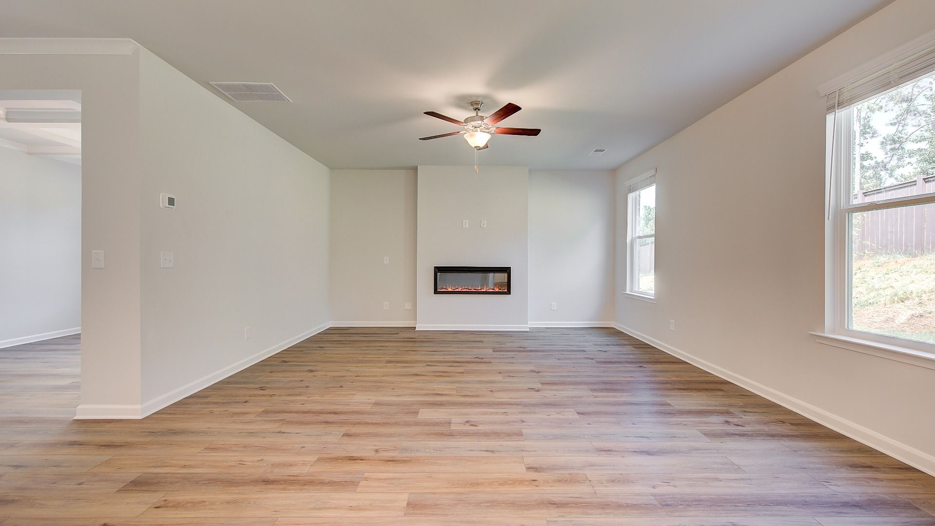 Bright modern family room with LVP flooring, fireplace, and natural light in the Wagener at Bowers Farm in McDonough, GA.