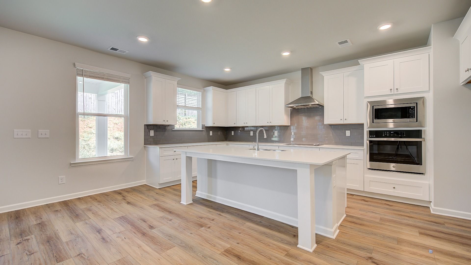 Open-concept Wagener kitchen with oversized island, pendant lighting, and bright white cabinetry at Bowers Farm.
