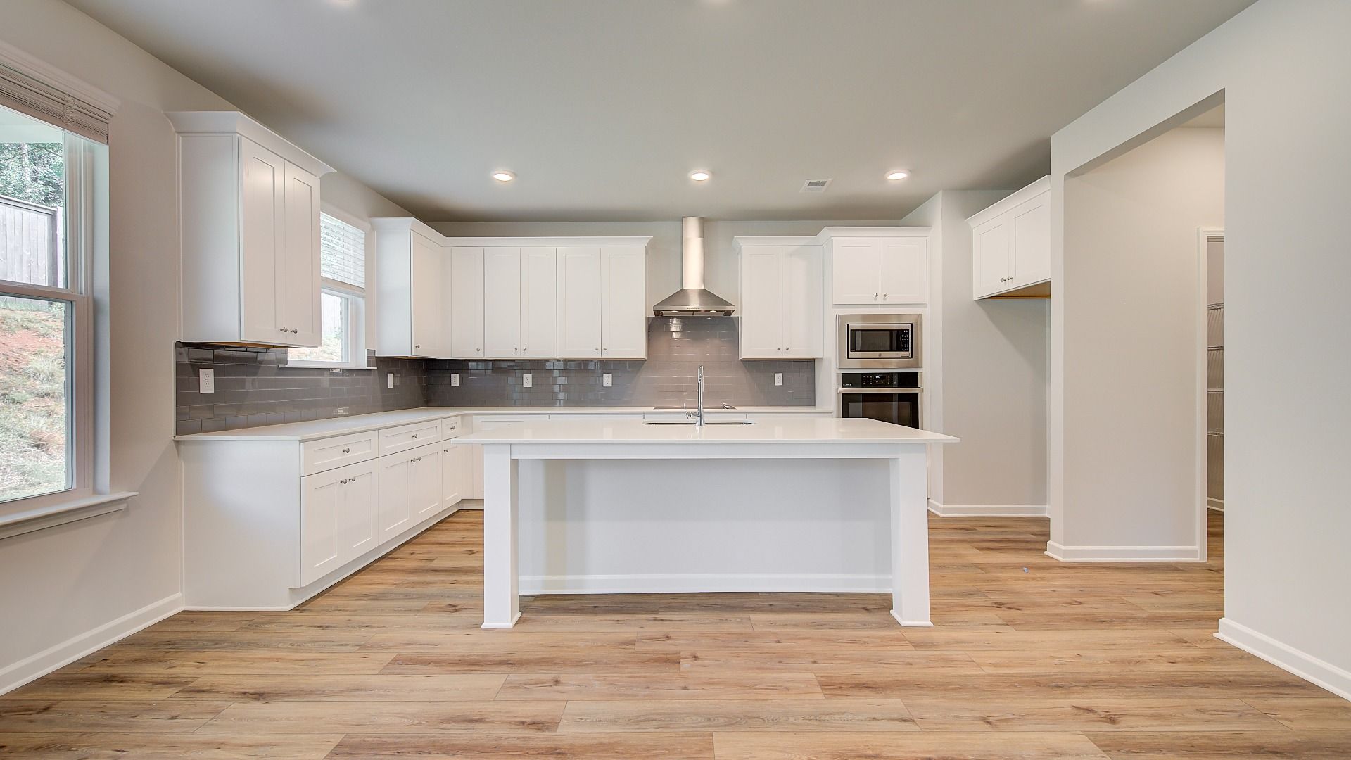 Open-concept Wagener kitchen with clean tile backsplash, white cabinetry, and large island with seating at Bowers Farm.