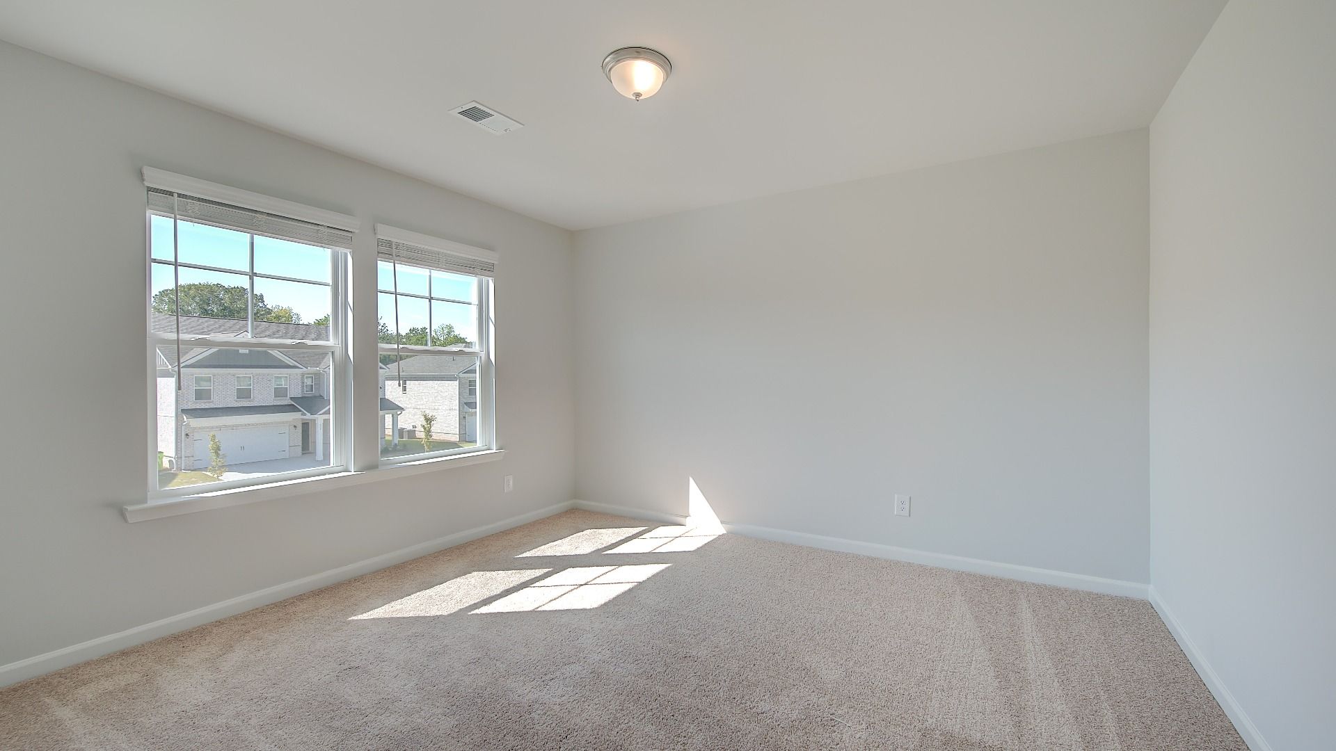 Comfortably sized secondary bedroom with carpet flooring, natural light, and modern finishes in the Wagener at Bowers Farm.