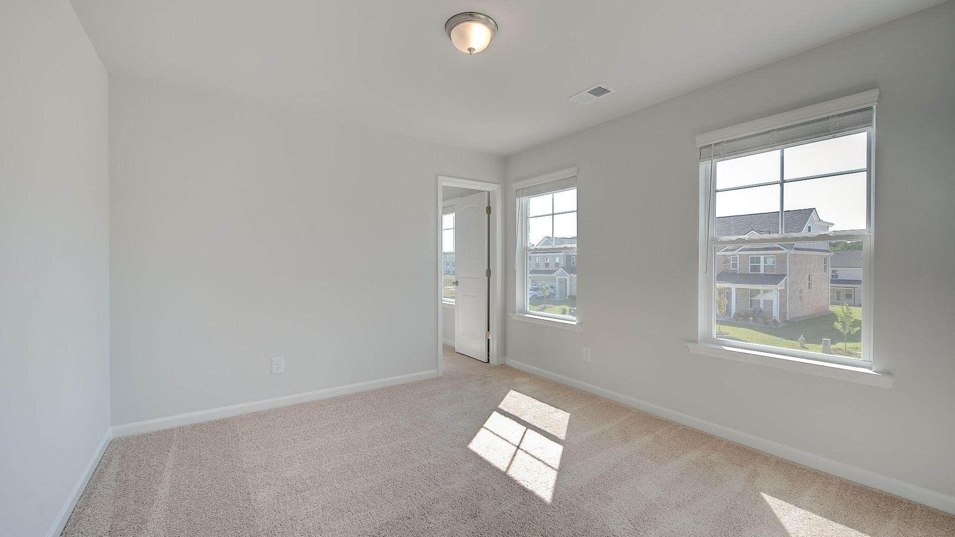 Spacious Wagener secondary bedroom with carpet flooring, natural light, and balcony access at Bowers Farm in McDonough, GA.
