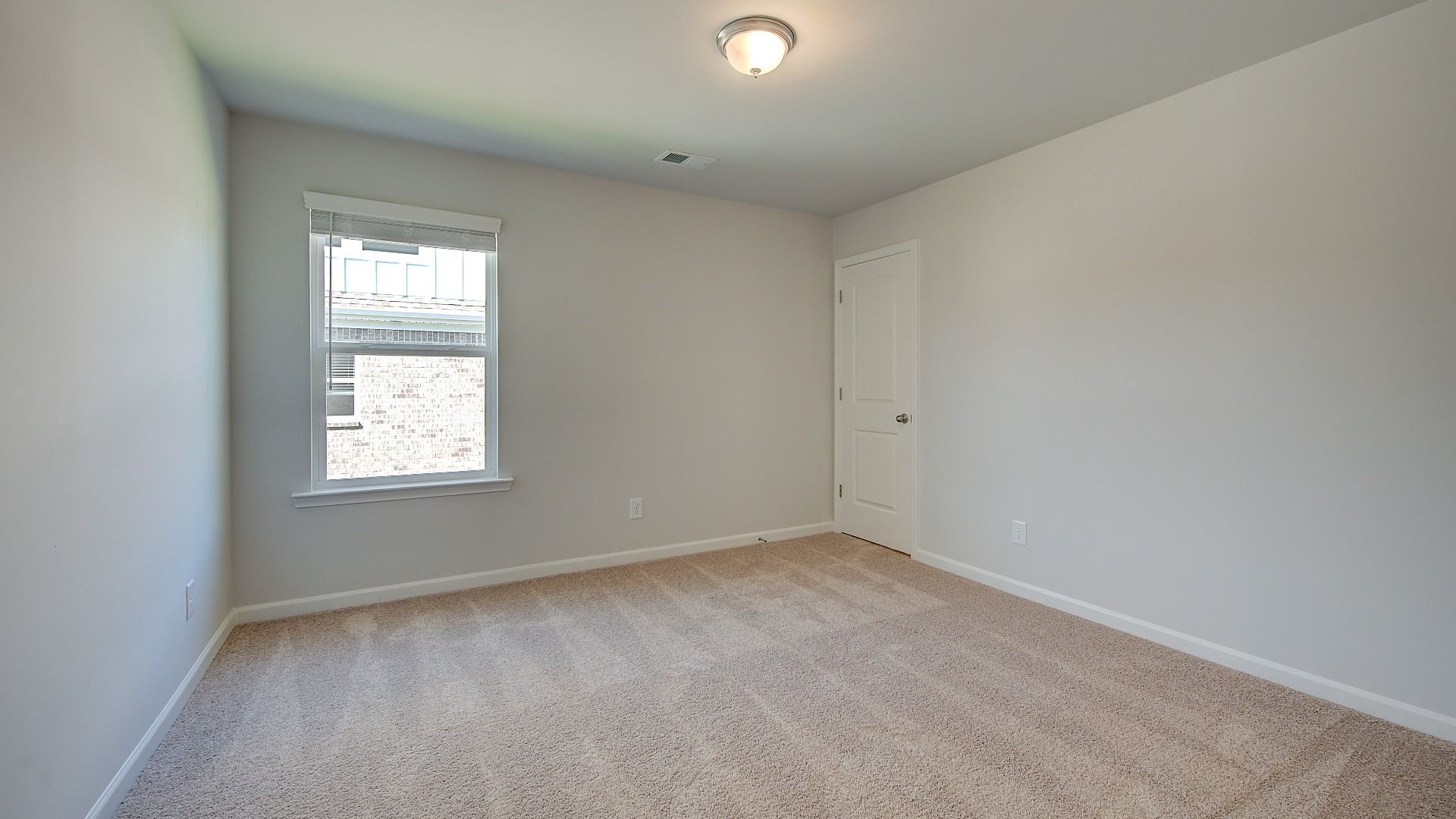 Wagener secondary bedroom with carpet flooring, abundant natural light, and neutral finishes at Bowers Farm in McDonough, GA.