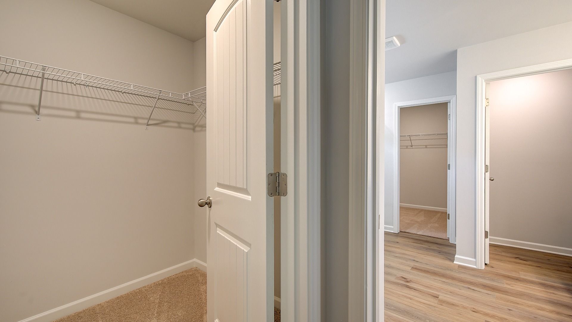 Wagener primary closet with built-in shelves for storage and carpet flooring at Bowers Farm in McDonough, GA.