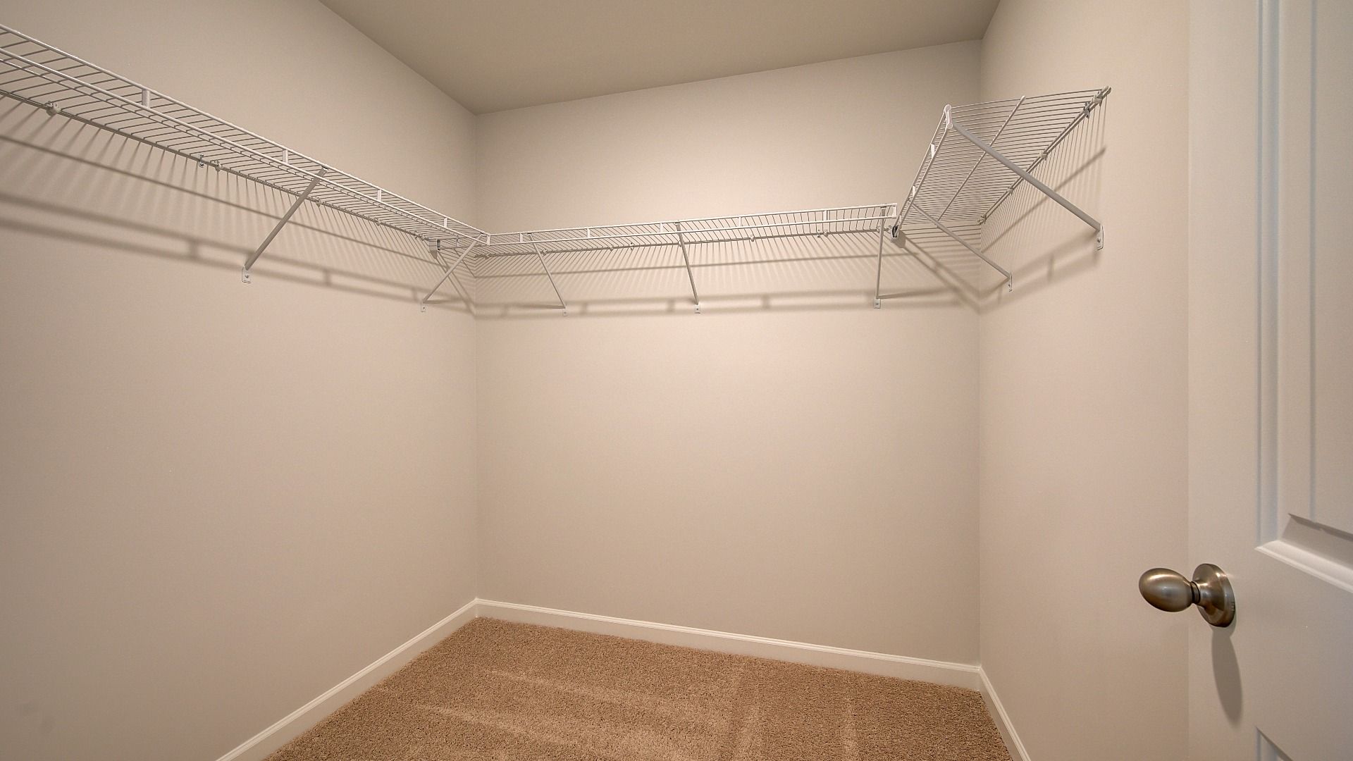 Spacious Wagener primary walk-in closet with built-in shelves and railings at Bowers Farm in McDonough, GA.