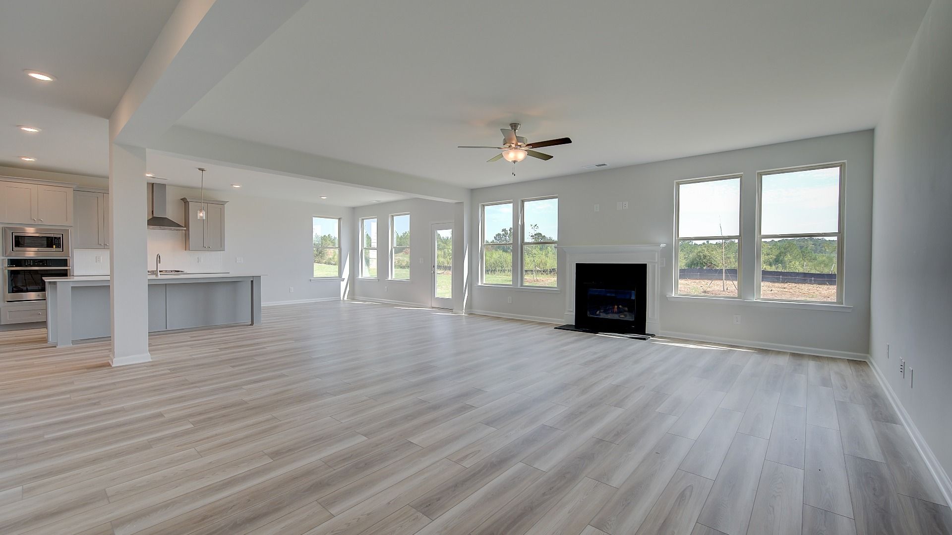 Open-concept family room with gas fireplace featuring brick surround and LVP flooring in the Clarity at Brighton.