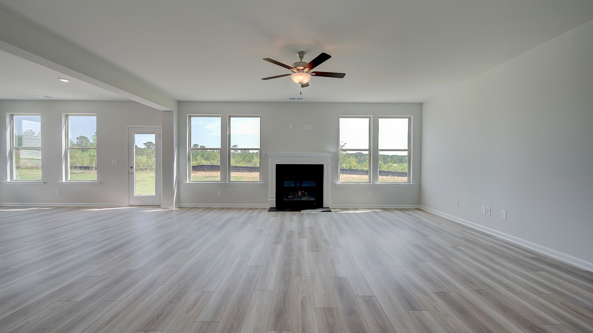 Expansive family room with shiplap wall accent, gas fireplace, and LVP flooring in Clarity at Brighton in Locust Grove, GA.