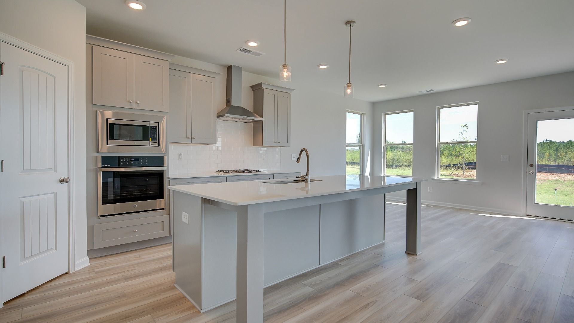 Open kitchen with large island, corner pantry, and stainless steel appliances in the Clarity at Brighton in Locust Grove, GA.
