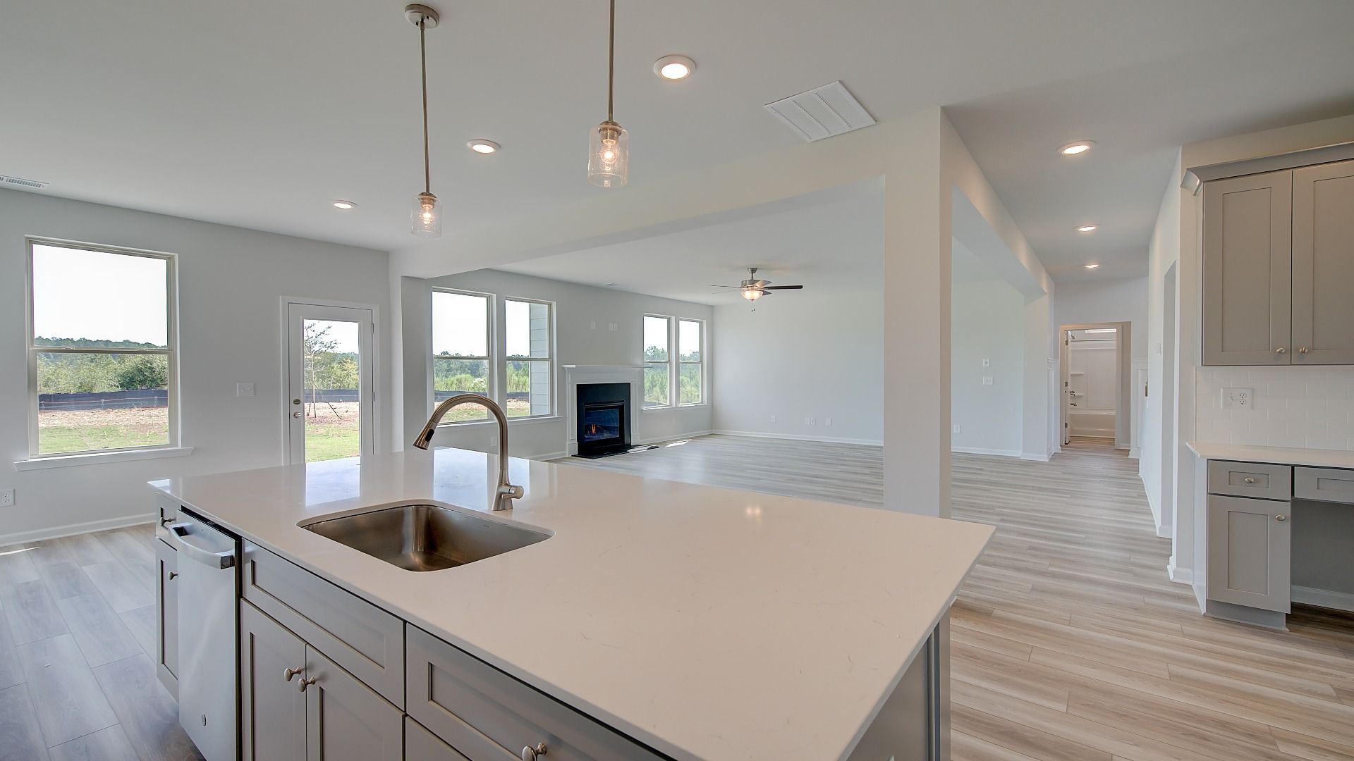Clarity kitchen with white tile backsplash and large island overlooking family room at Brighton in Locust Grove, GA.