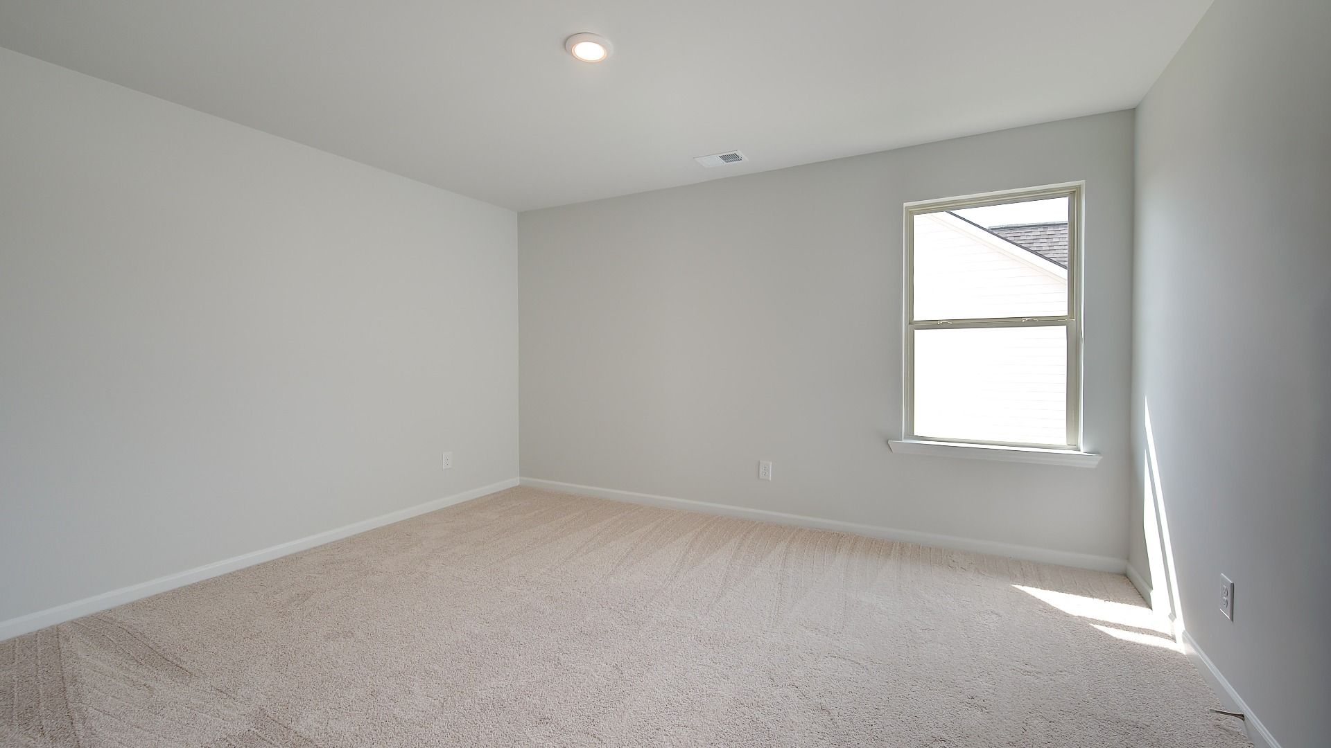 Carpeted secondary bedroom with neutral walls and natural light in the Clarity at Brighton in Locust Grove, GA.