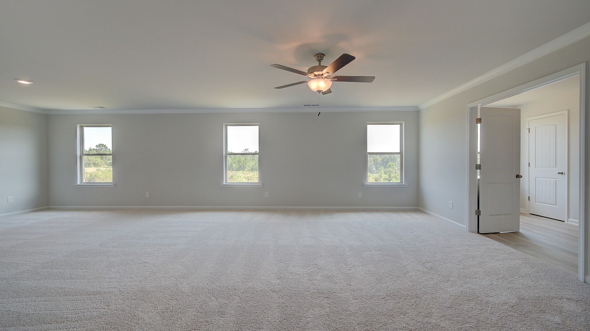 Expansive primary suite with carpet flooring, overhead fan light, and connecting bath in the Clarity at Brighton.