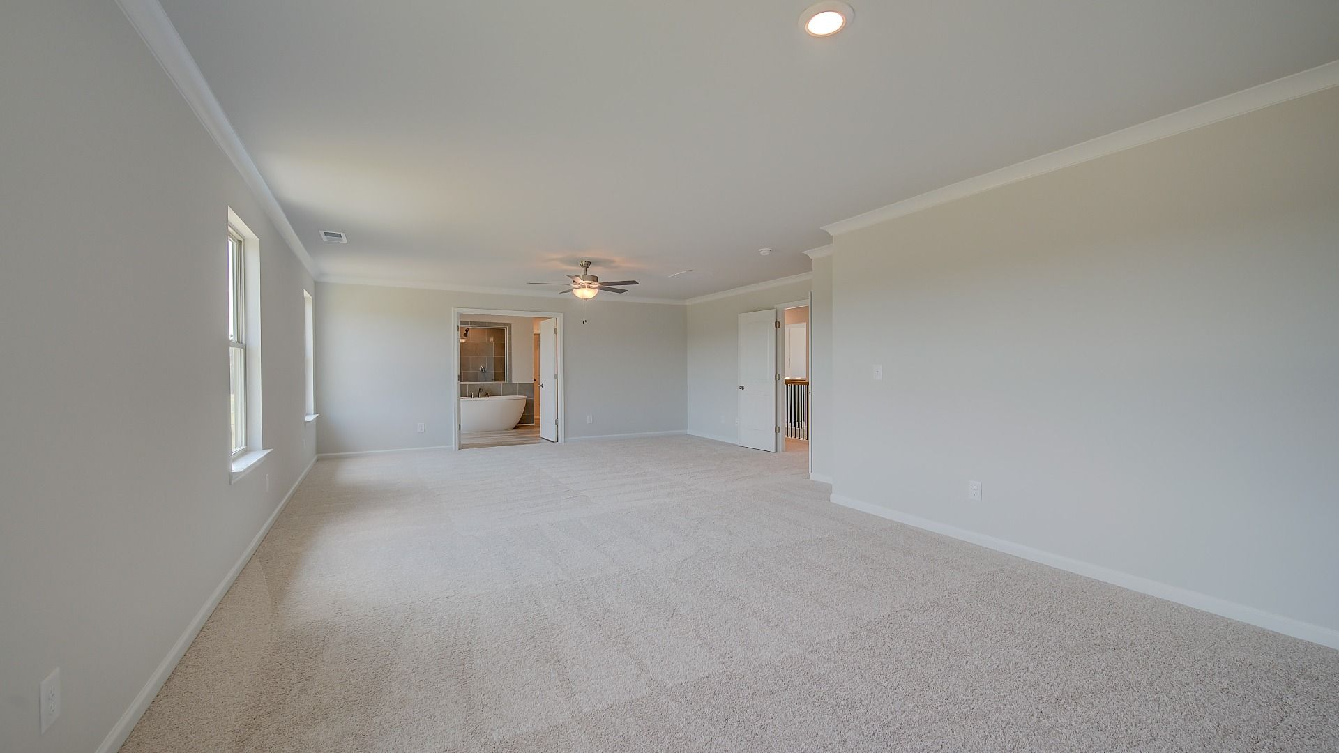 Spacious primary suite with sitting room, carpet flooring, and natural light in the Clarity at Brighton in Locust Grove, GA.