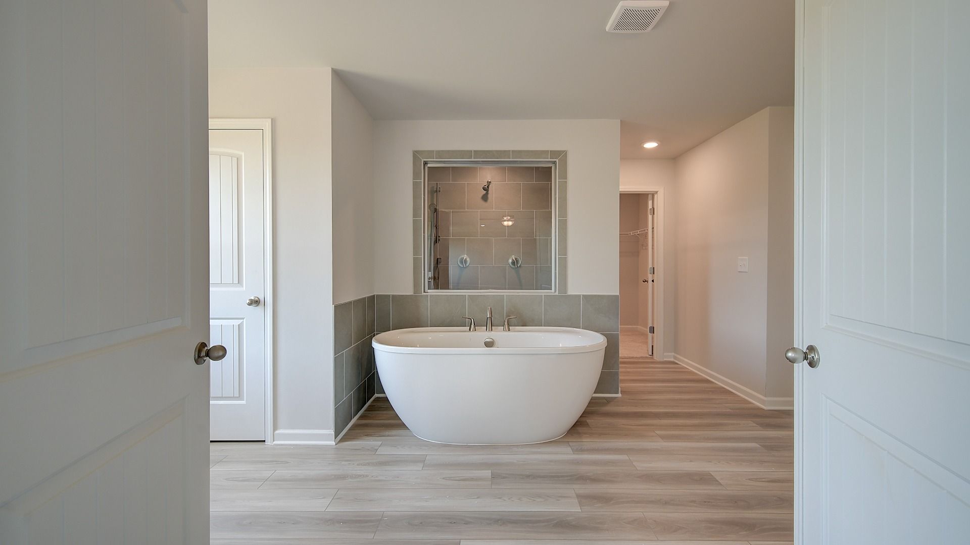 Primary bath with modern tile floor, tiled accent wall, and freestanding tub in the Clarity at Brighton in Locust Grove, GA.