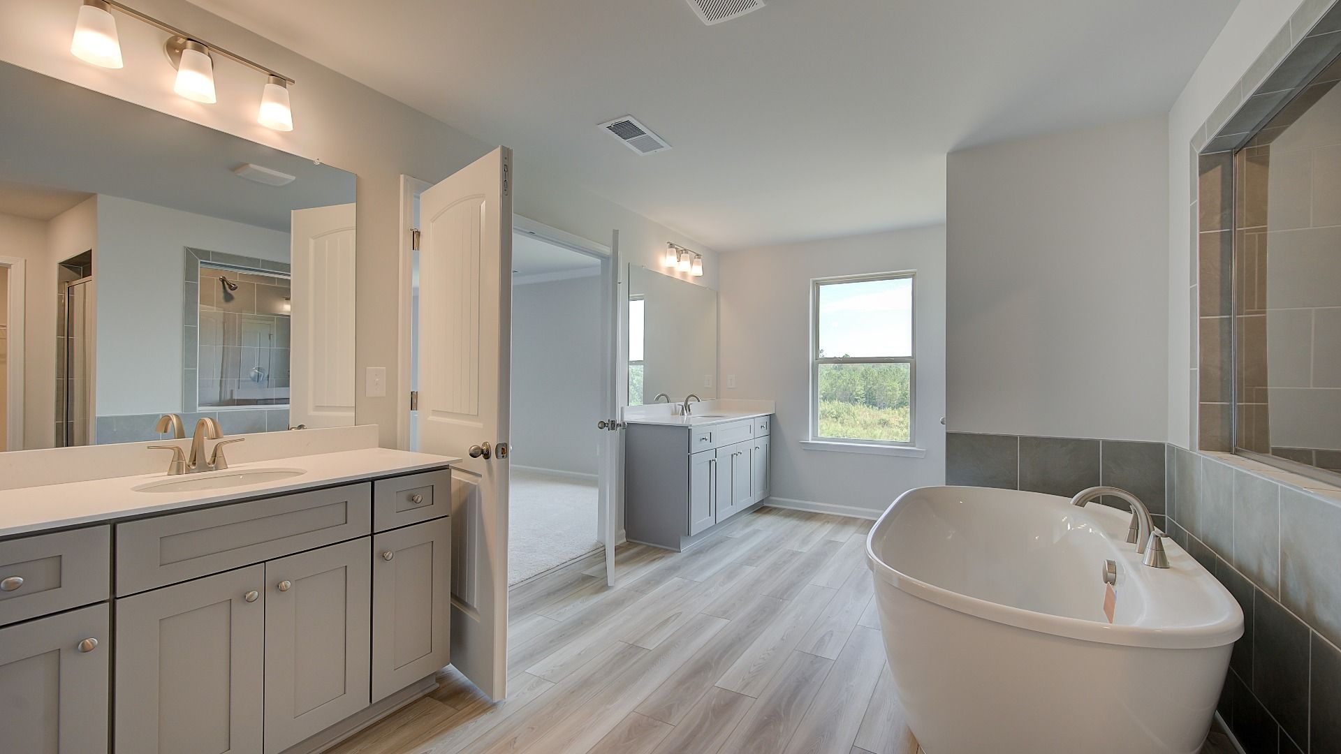 Luxury primary bath with dual vanities, freestanding tub, and neutral modern finishes in the Clarity at Brighton.