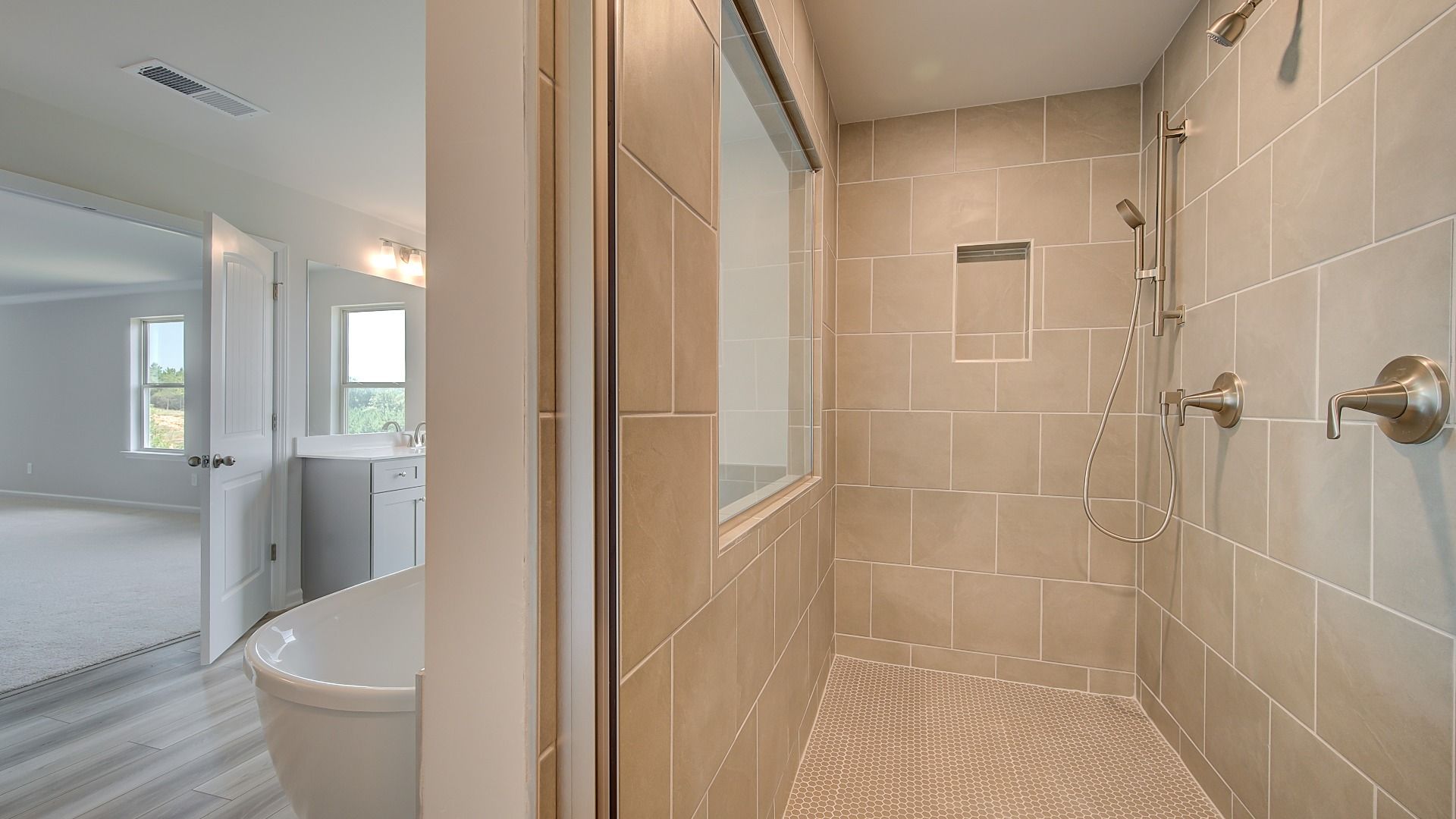 Primary bath with dual vanities, freestanding tub, and neutral modern finishes in the Clarity at Brighton.