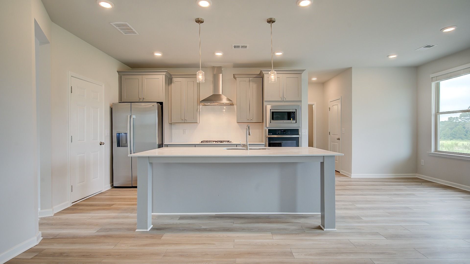 Open-concept kitchen with oversized island, white cabinetry, and stainless steel appliances in the Meridian II at Brighton.