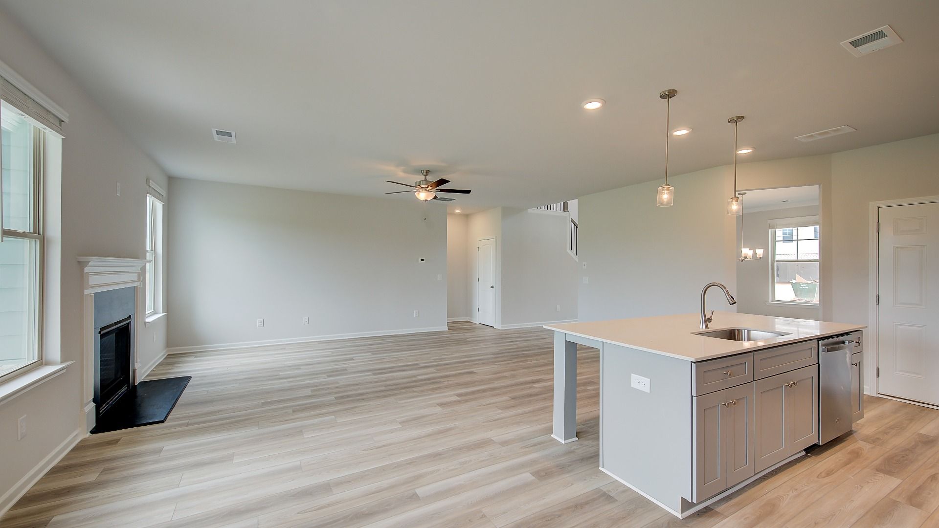 Meridian II open-concept living space connecting kitchen and family room with LVP flooring at Brighton in Locust Grove, GA.