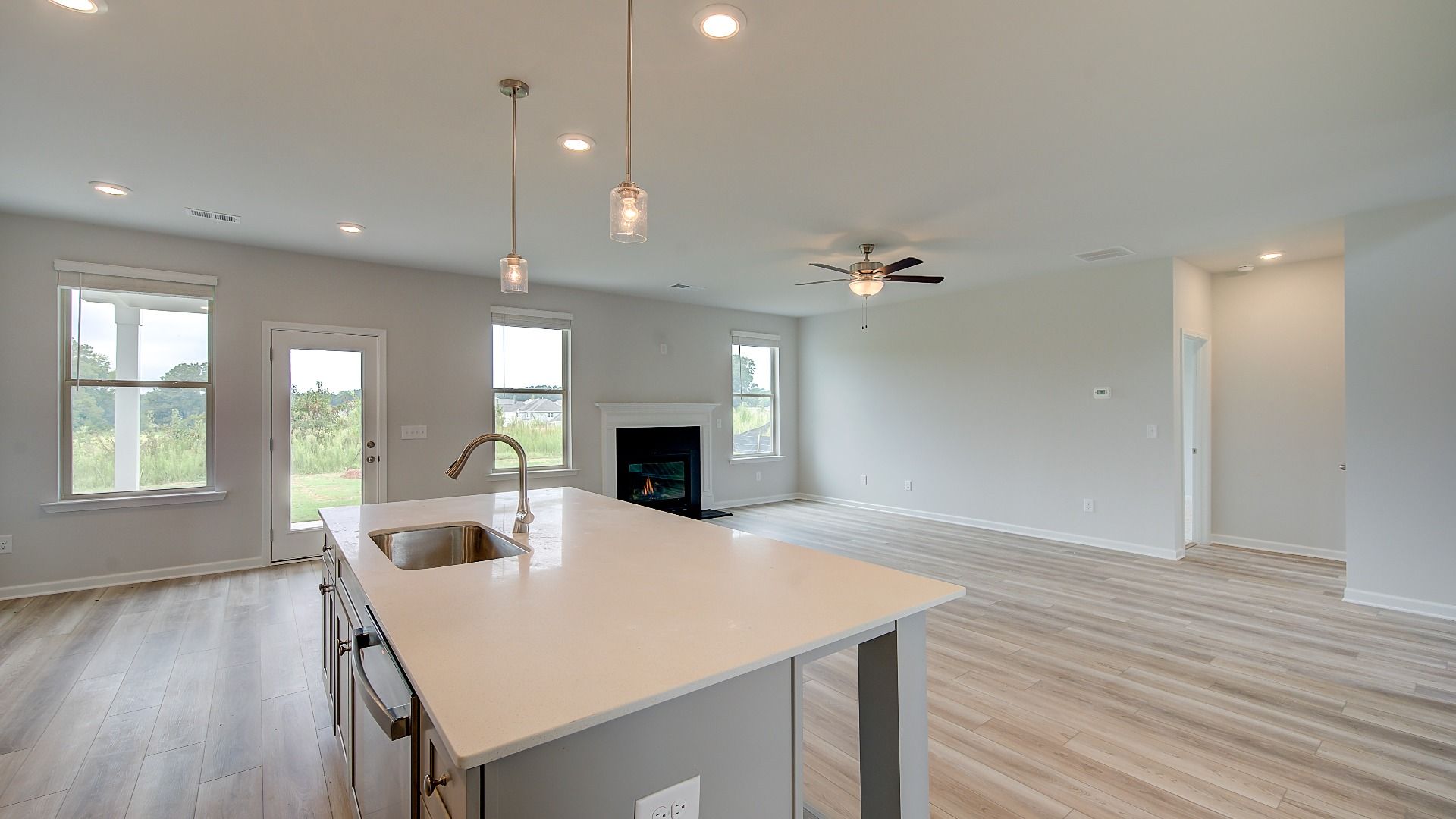 Meridian II open-concept living space connecting kitchen and family room with LVP flooring at Brighton in Locust Grove, GA.
