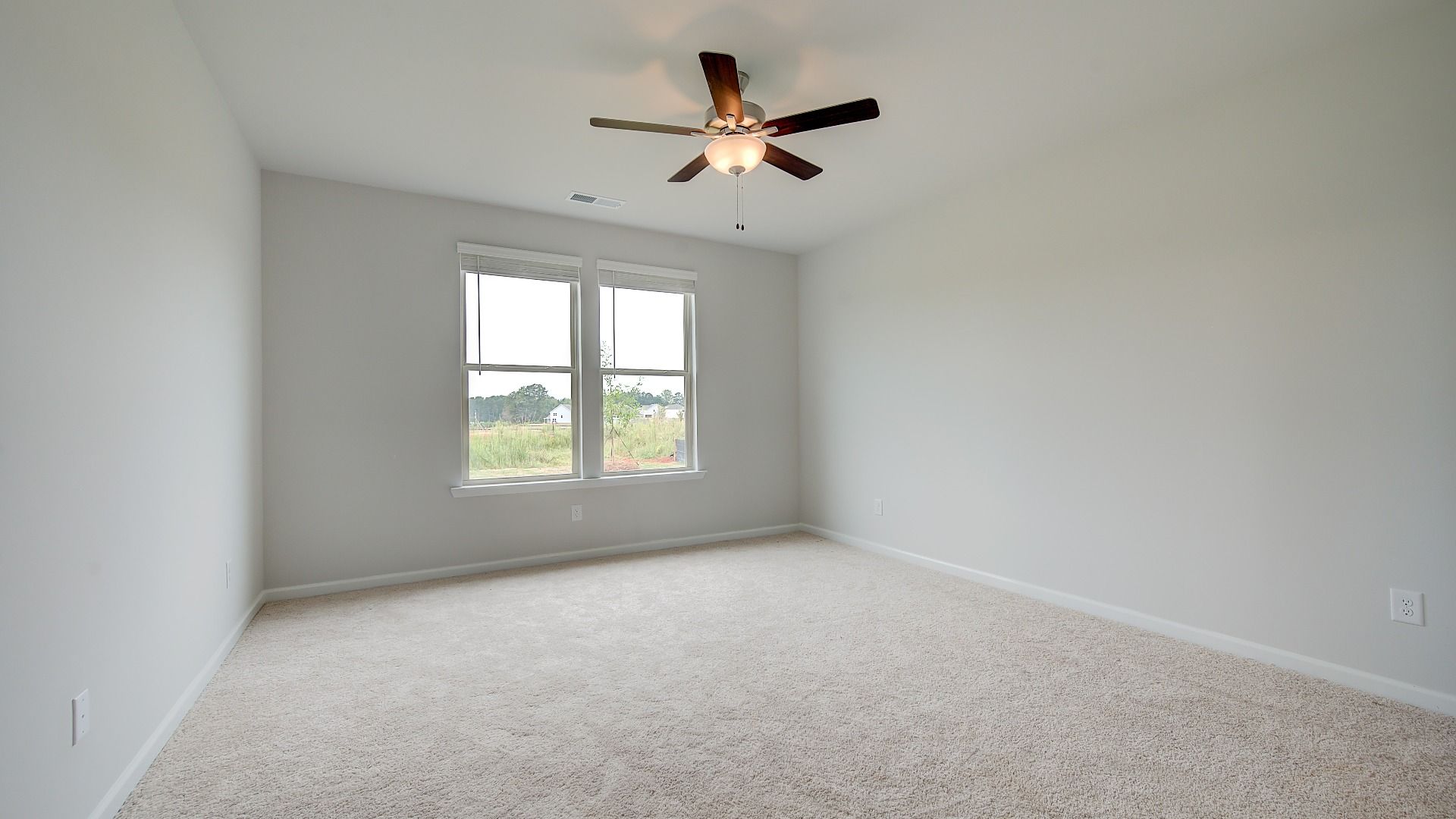 Spacious Meridian II primary suite with coffered ceiling, carpet flooring, and bay window at Brighton in Locust Grove, GA.