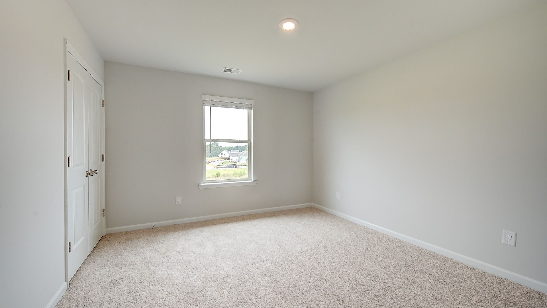 Secondary bedroom with carpet flooring and window providing natural light in the Meridian II at Brighton in Locust Grove, GA.