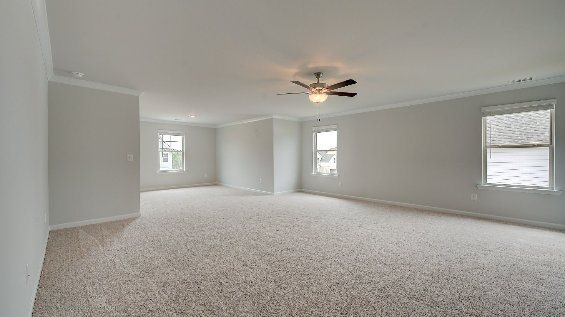 Expansive primary suite with carpet flooring, connected seating room, and ceiling fan light in the Meridian II at Brighton.