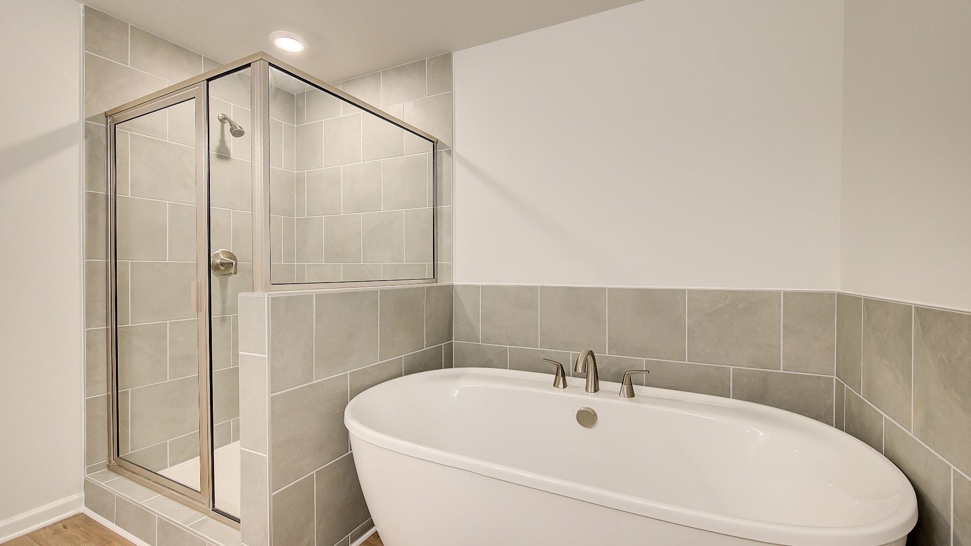 Luxury Meridian II primary bath with modern tile throughout floors, tub surround, and walk-in shower at Brighton.