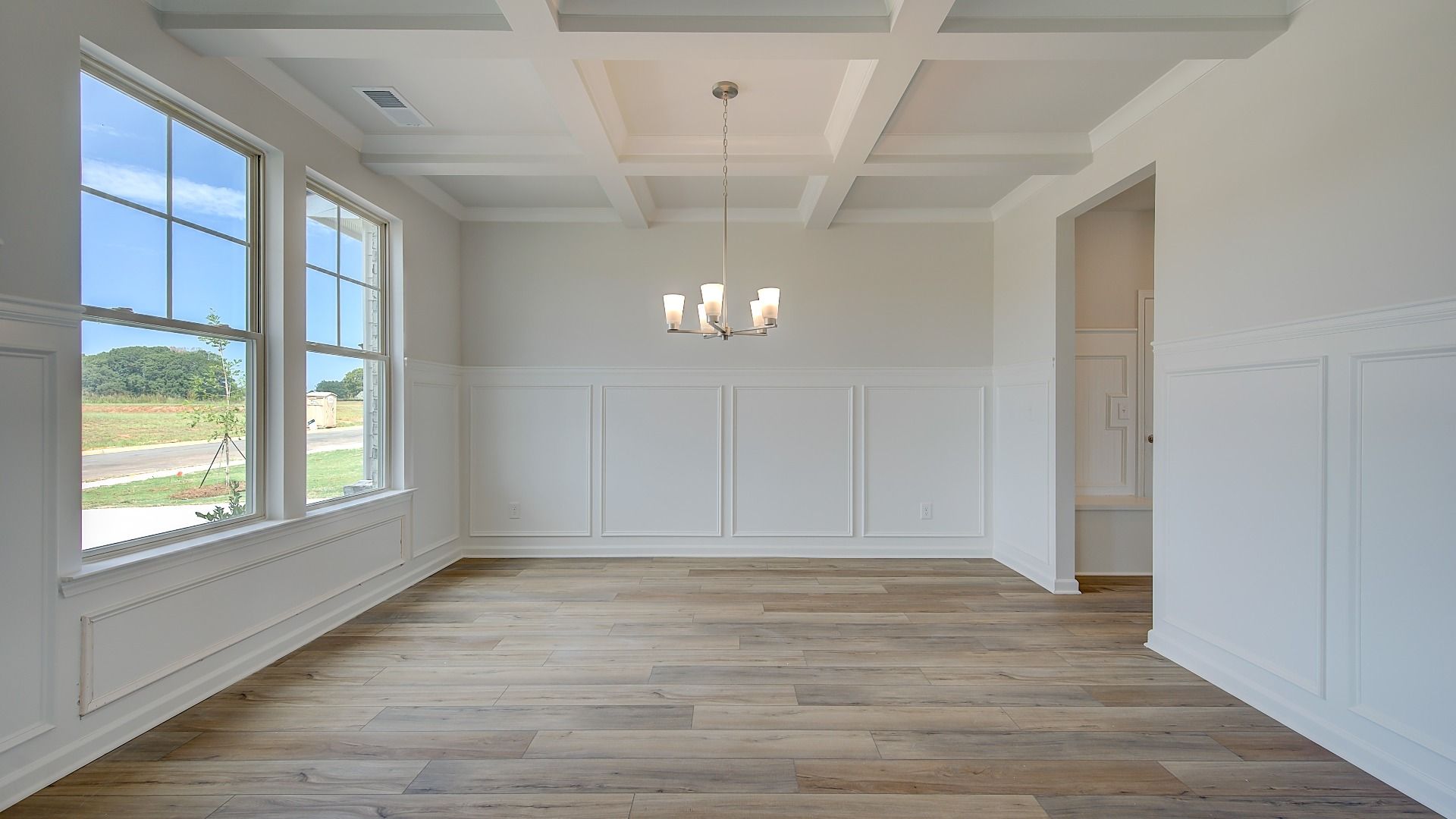 Stonefield dining room with coffered ceiling, box panel wainscoting, and LVP flooring at Brighton in Locust Grove, GA.