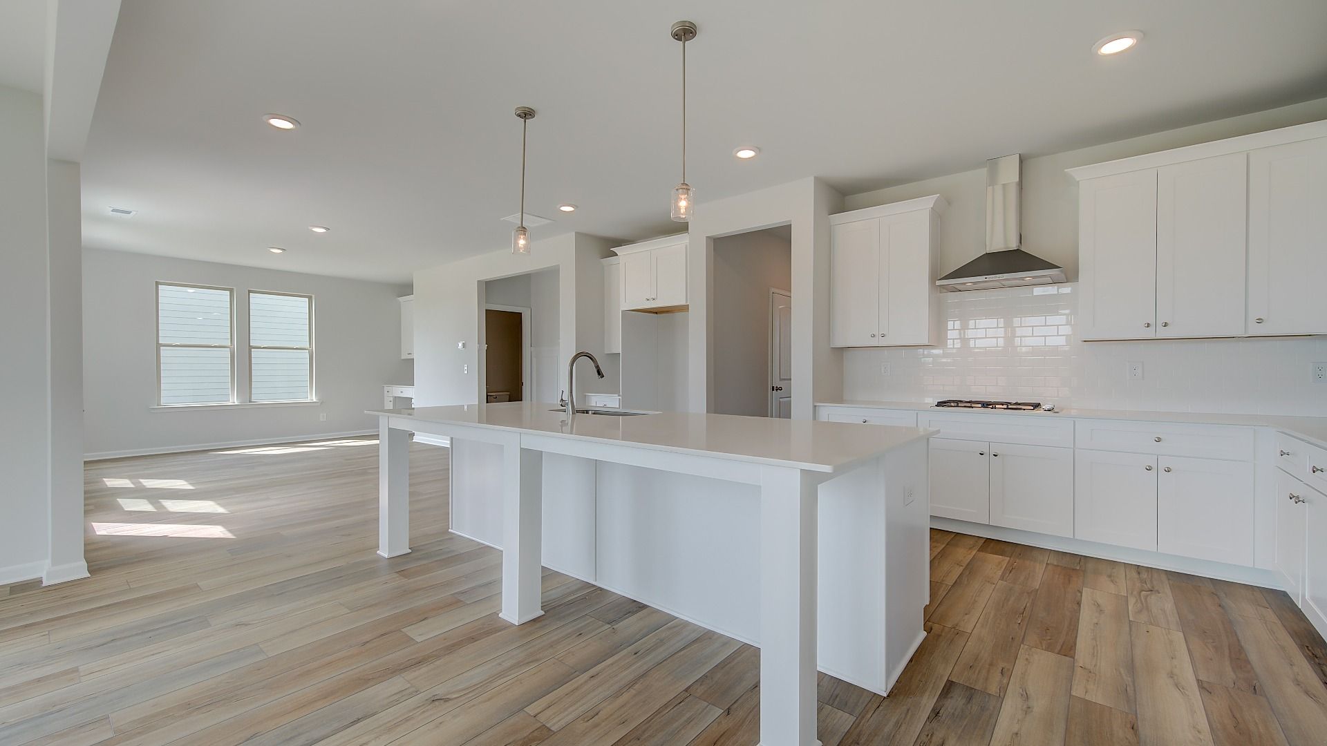 Stonefield kitchen with oversized island, neutral cabinetry, and tile backsplash at Brighton in Locust Grove, GA.
