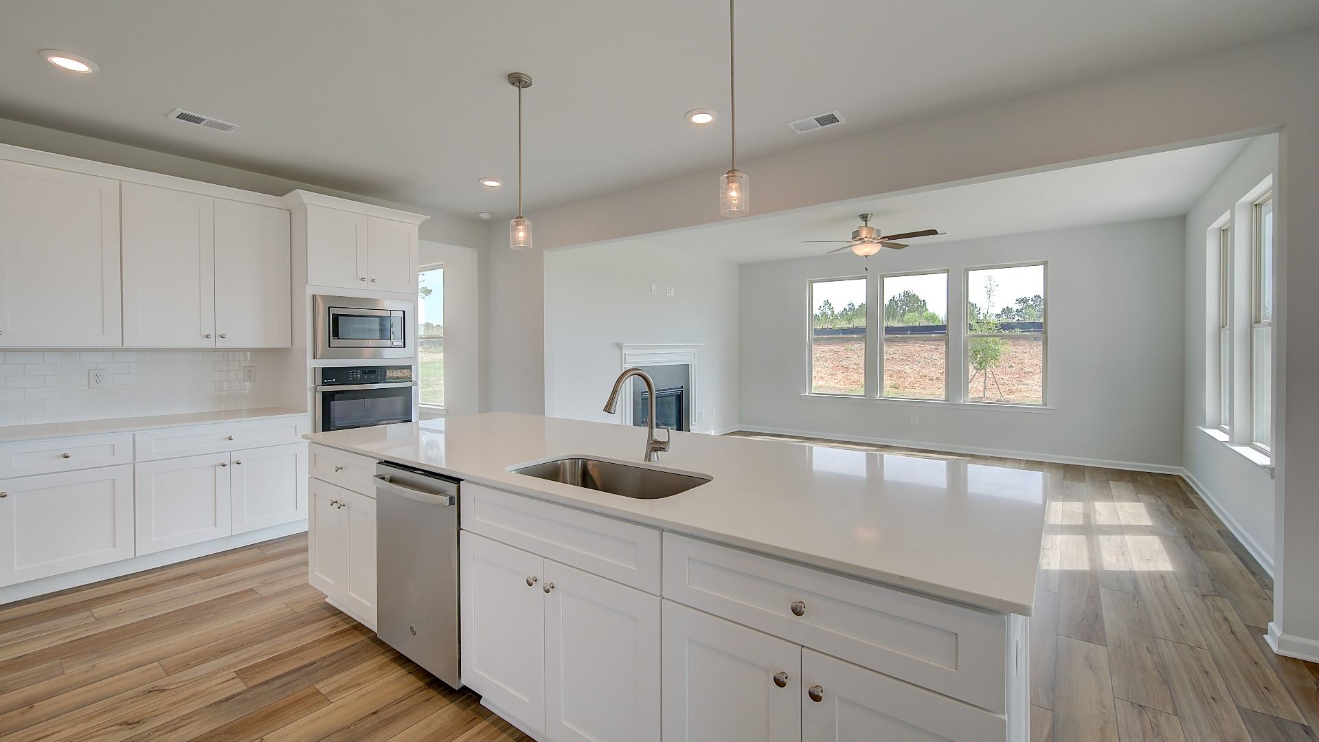 Stonefield open-concept kitchen with large island, neutral cabinetry, and pendant lighting at Brighton in Locust Grove, GA.