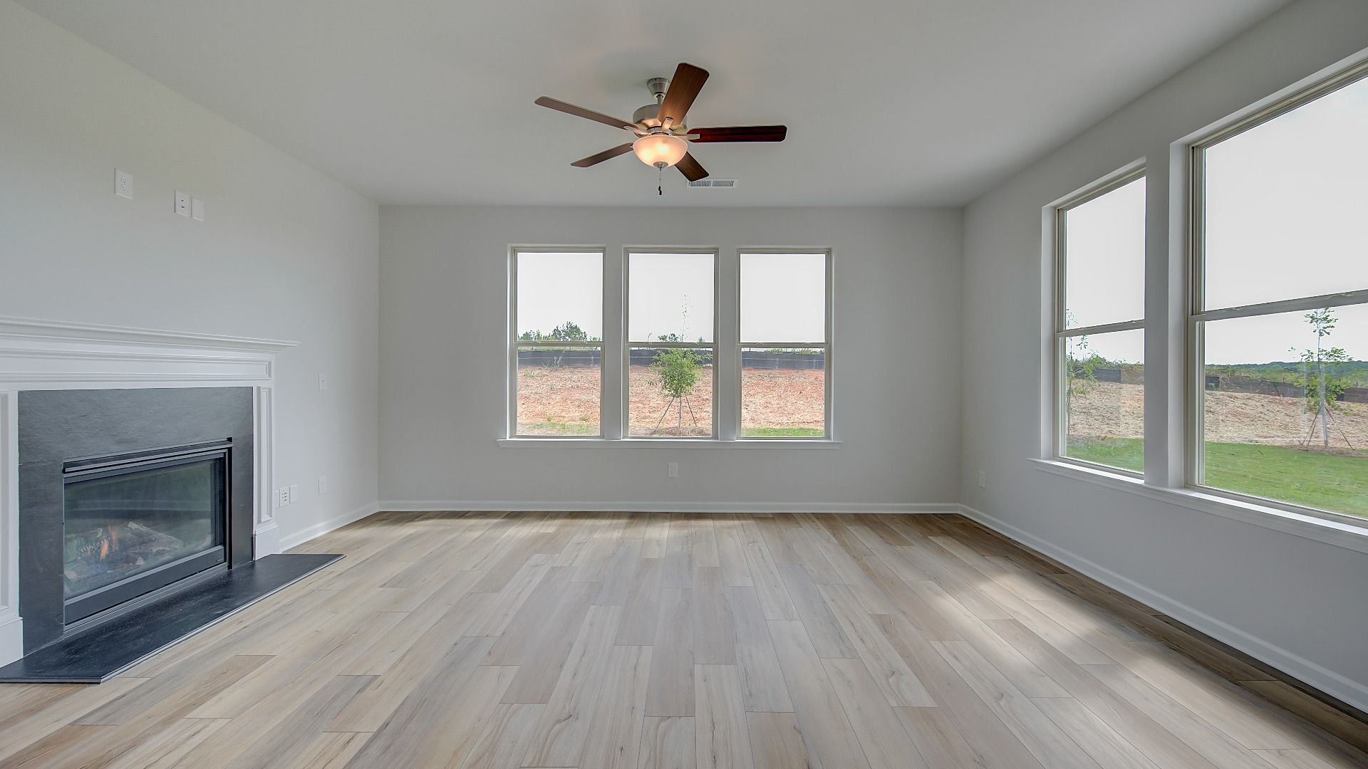Stonefield expansive family room with abundant natural light, gas fireplace, and LVP flooring at Brighton.