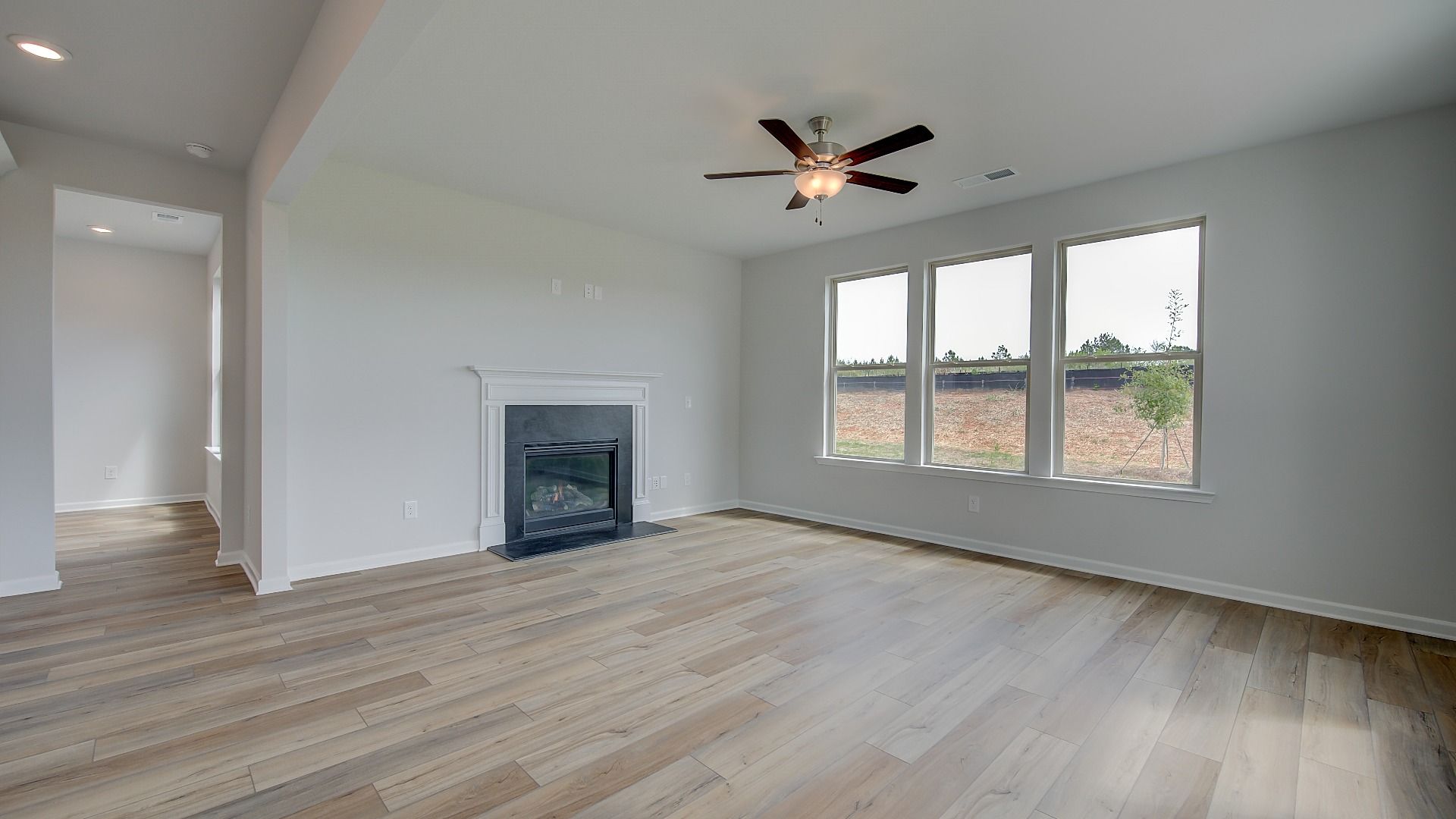 Stonefield open-concept family room with gas fireplace, LVP flooring, and connection to kitchen at Brighton.
