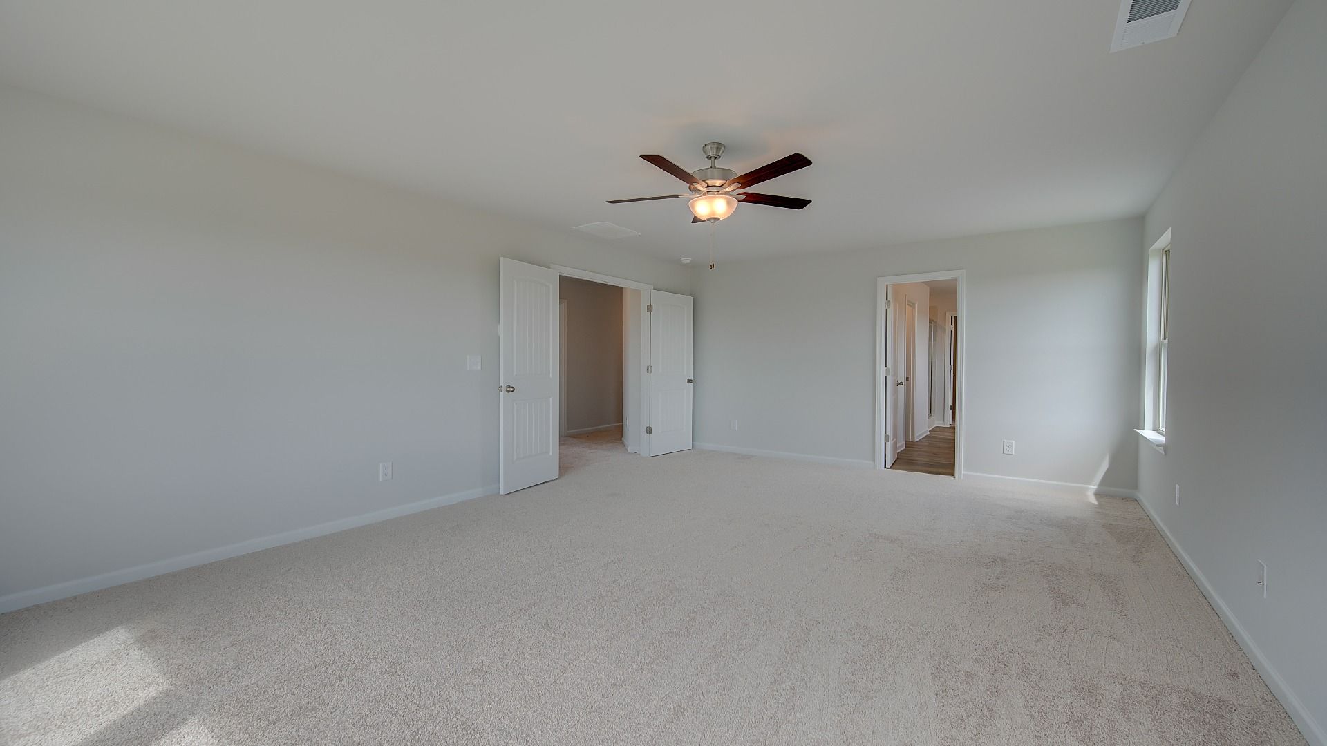 Stonefield double-door entry primary suite with tray ceiling, carpet flooring, and spacious layout at Brighton.