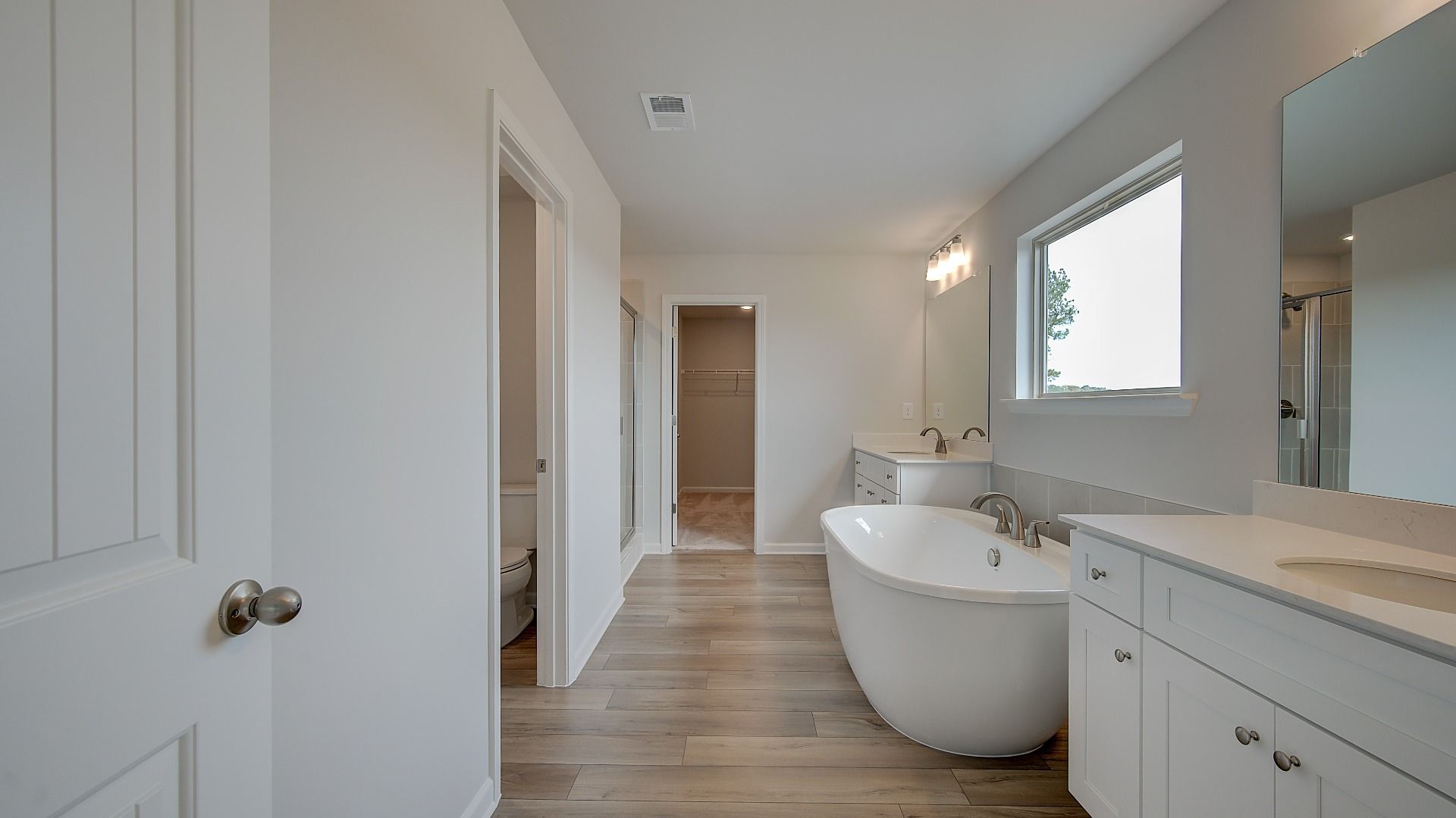 Primary bath with modern tile flooring, freestanding tub, and dual vanities in the Stonefield at Brighton.