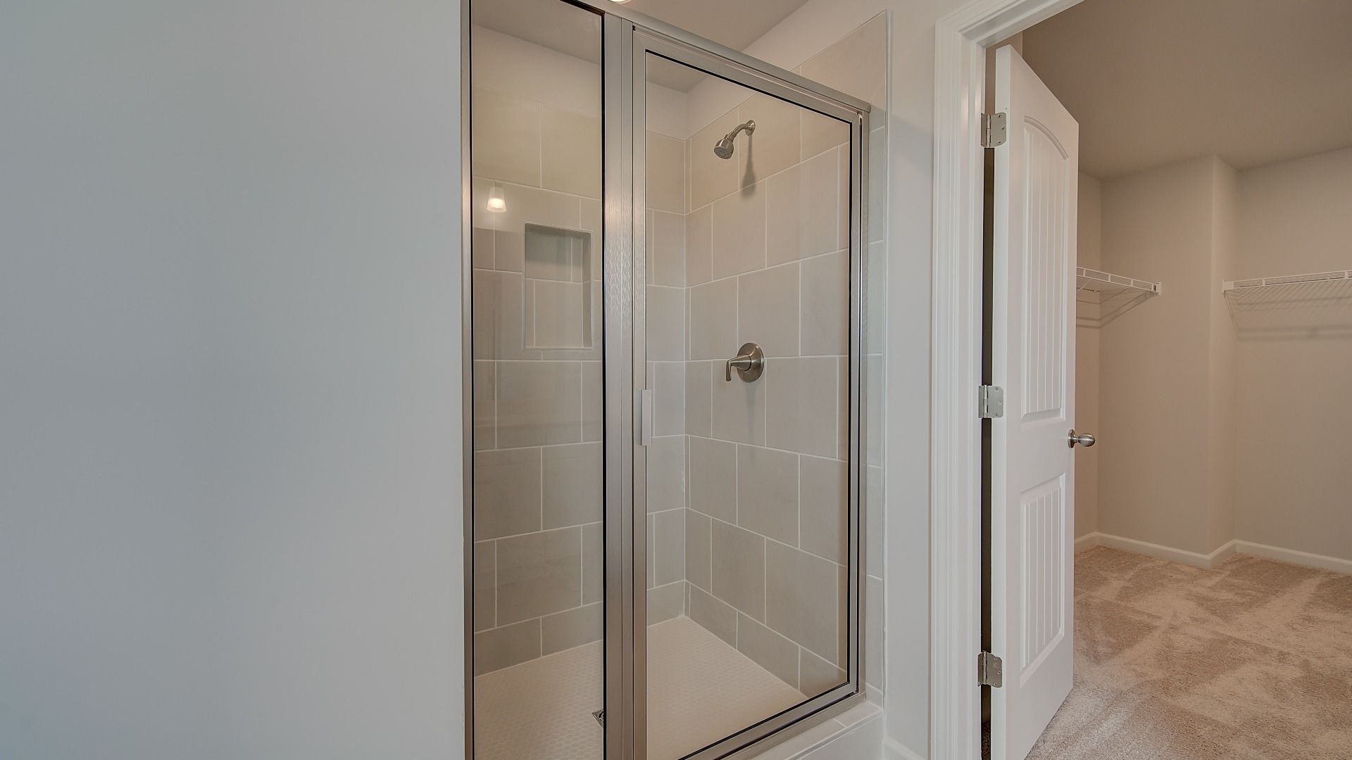 Primary bath with tiled walk-in shower and connected closet in the Stonefield at Brighton in Locust Grove, GA.