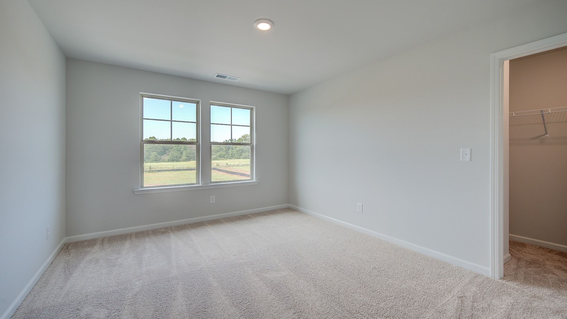 Secondary bedroom with natural light, tray ceiling, and carpet flooring in the Stonefield at Brighton in Locust Grove, GA.