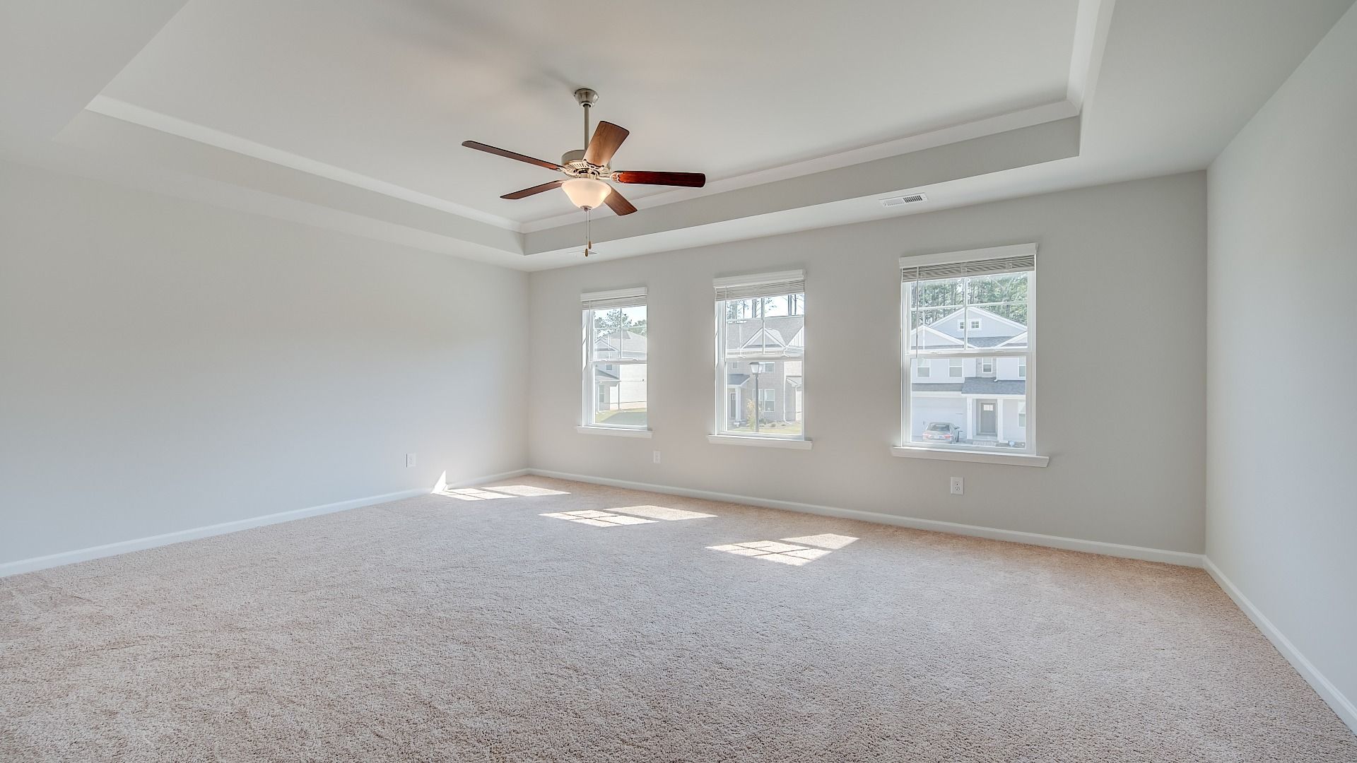 Spacious Ridgewood primary suite with tray ceiling, carpet flooring, and abundant natural light at Bowers Farm.