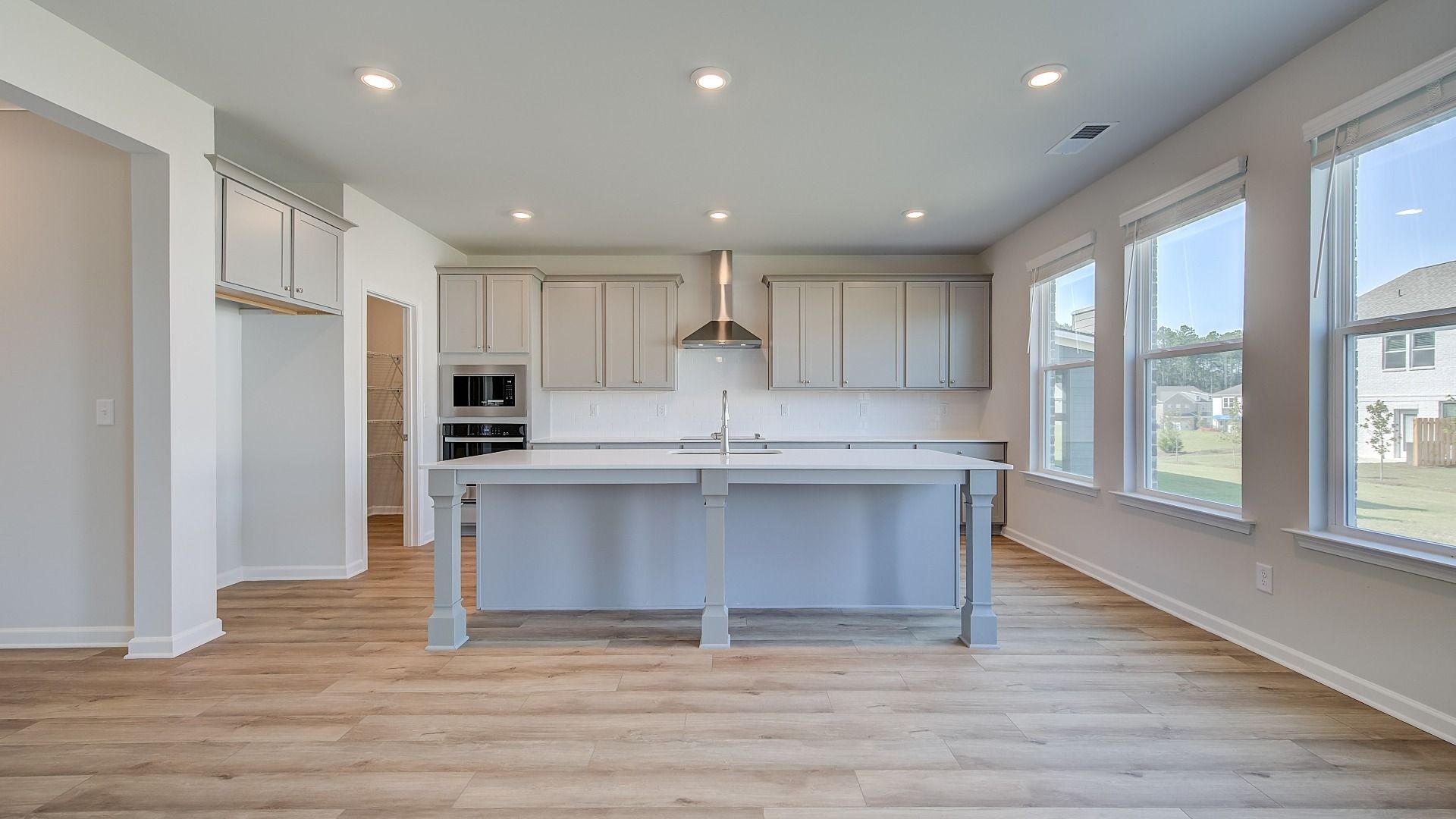 Open Ridgewood kitchen with grey cabinetry, tile backsplash, and oversized island with seating at Bowers Farm.
