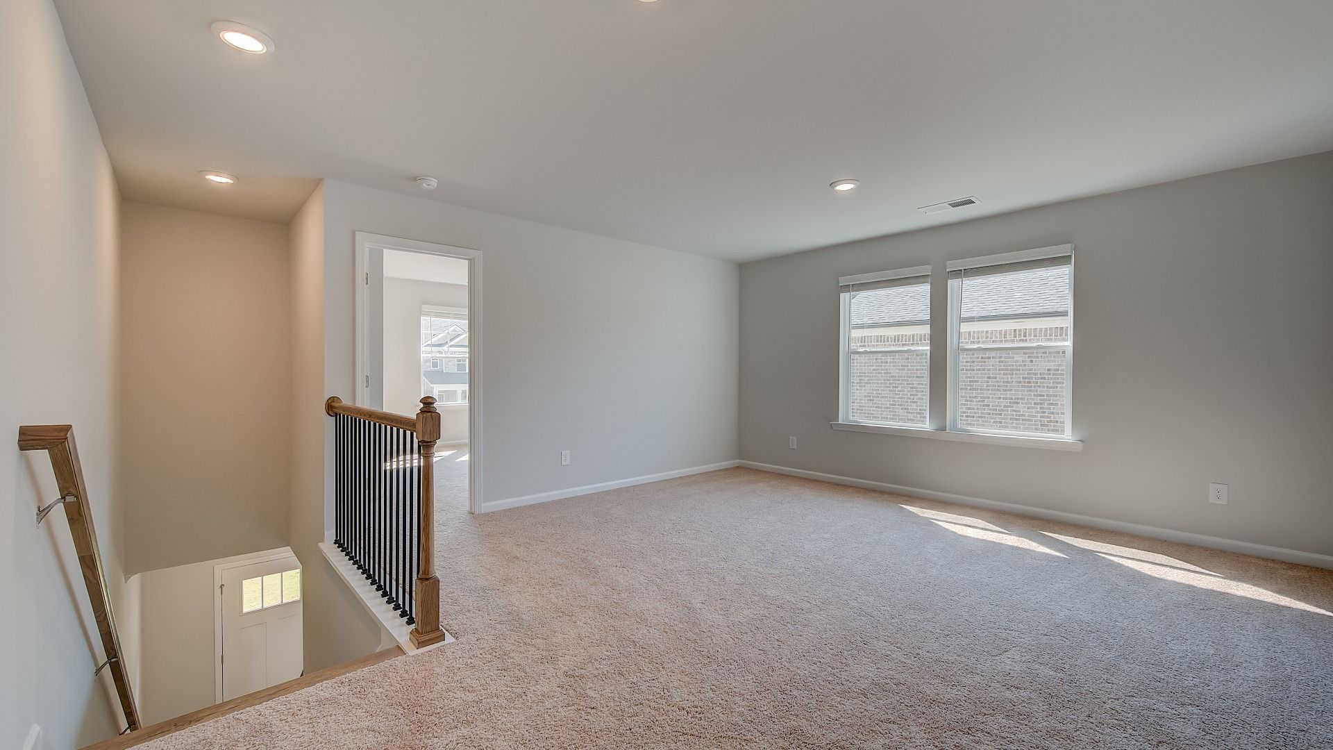 Spacious Ridgewood loft for work or lounge use with carpet flooring and natural light at Bowers Farm in McDonough, GA.