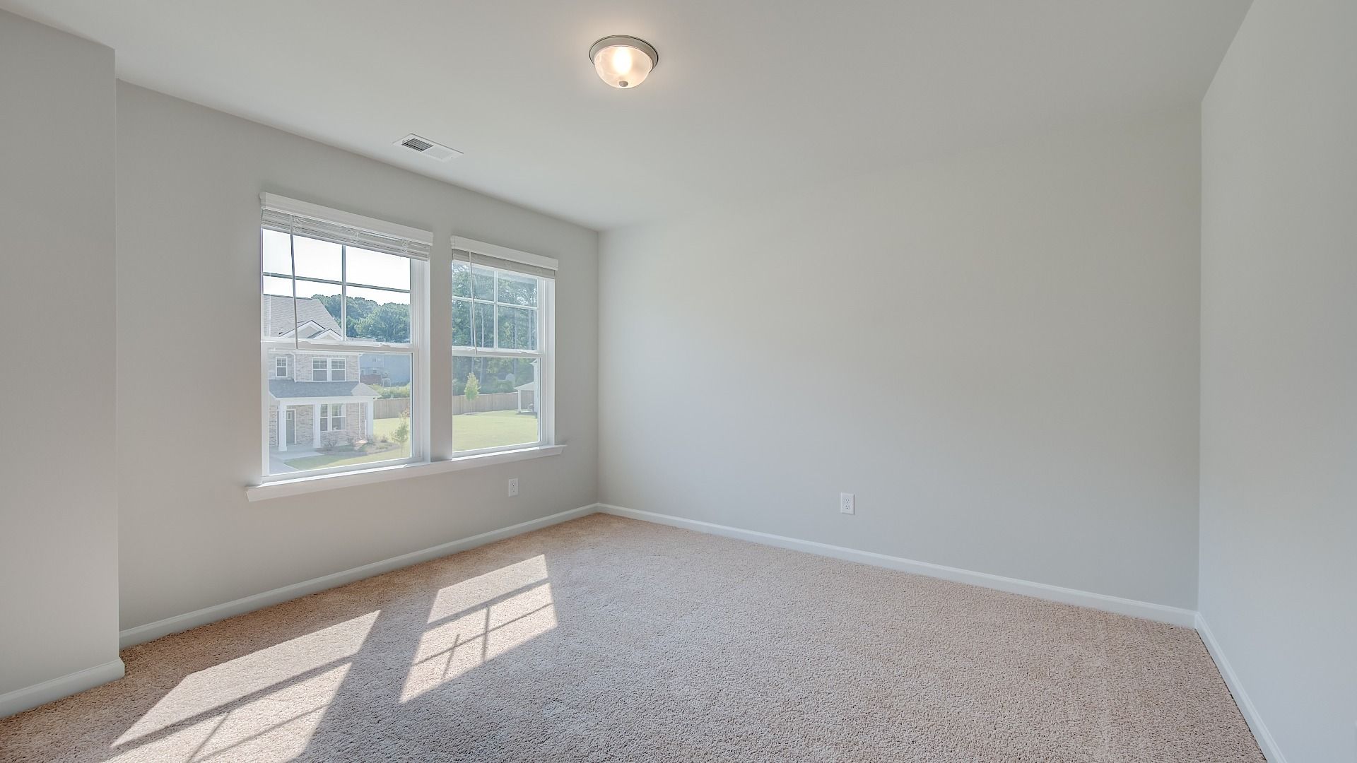 Comfortably sized Ridgewood secondary bedroom with carpet flooring and natural light at Bowers Farm in McDonough, GA.