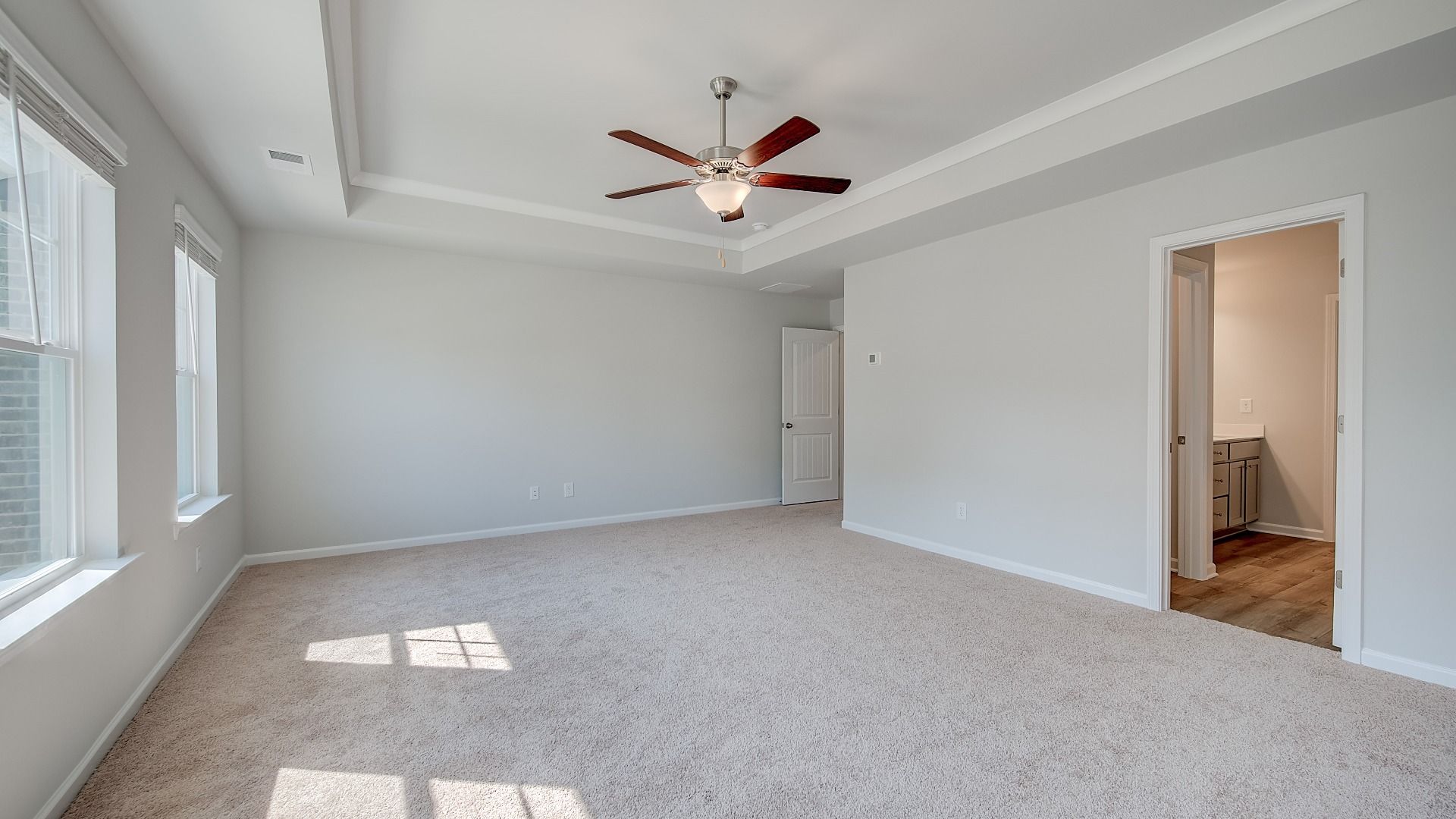 Spacious Ridgewood primary suite with tray ceiling, carpet flooring, and neutral modern finishes at Bowers Farm.