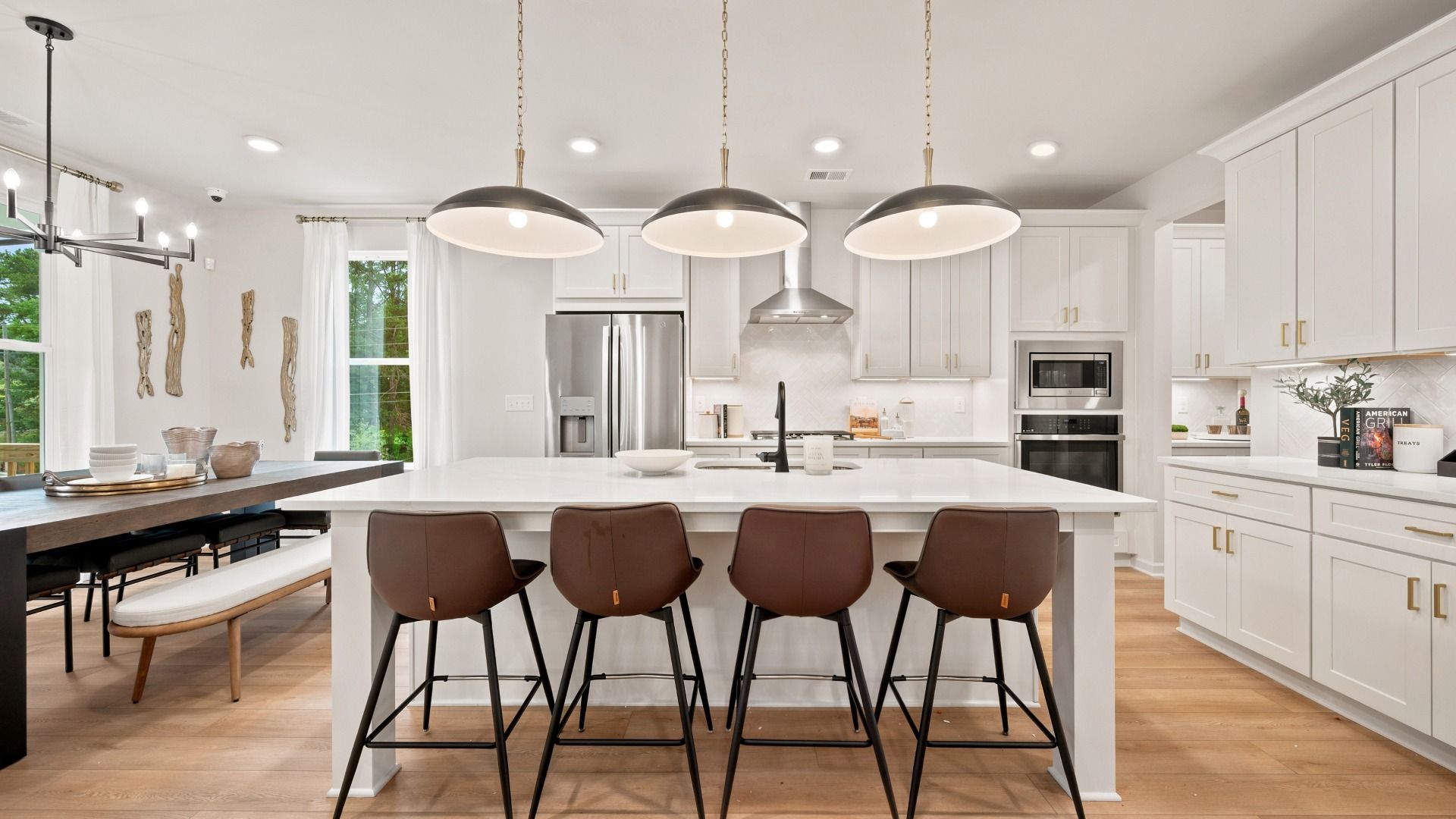Rosemary II kitchen with white cabinetry, LVP flooring, and expansive island with seating at Brighton in Locust Grove, GA.