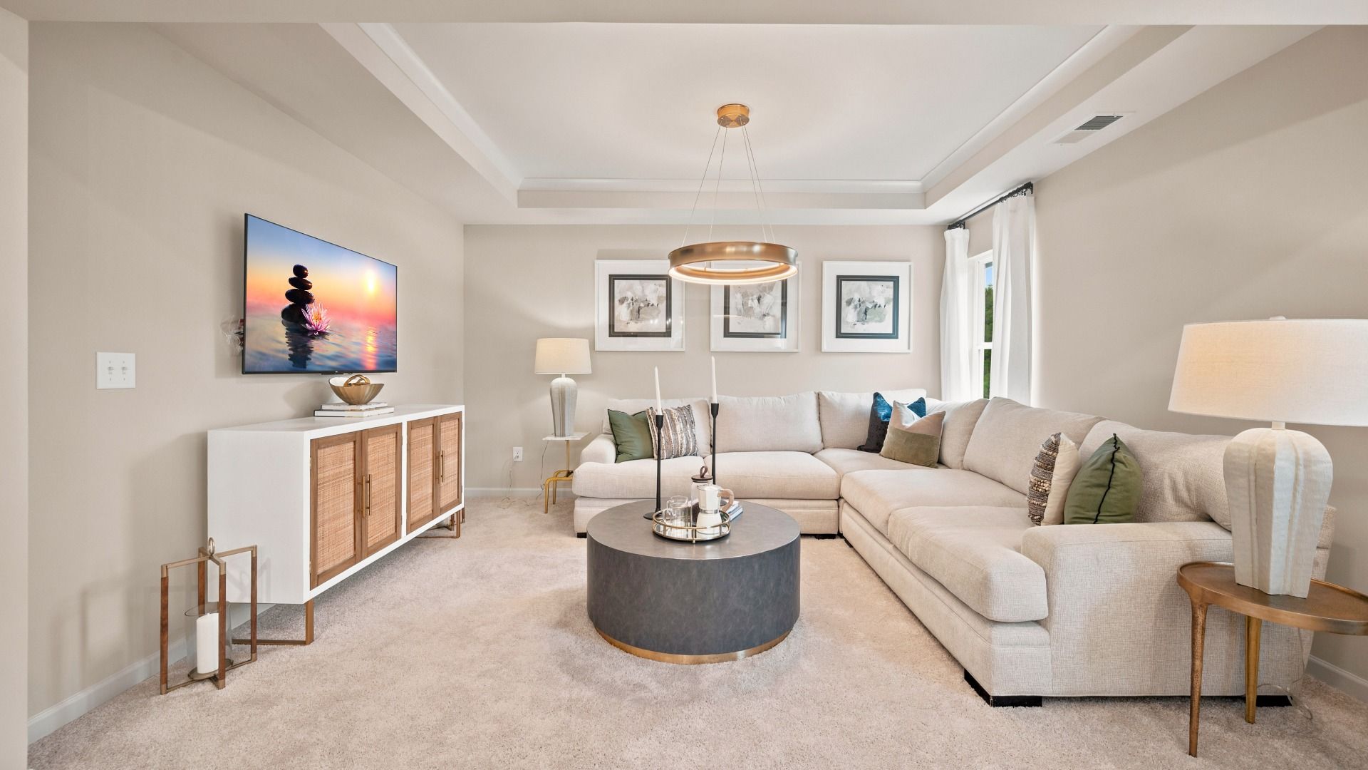 Rosemary II primary suite spacious sitting room with tray ceiling, wall panel molding, and carpet flooring at Brighton.