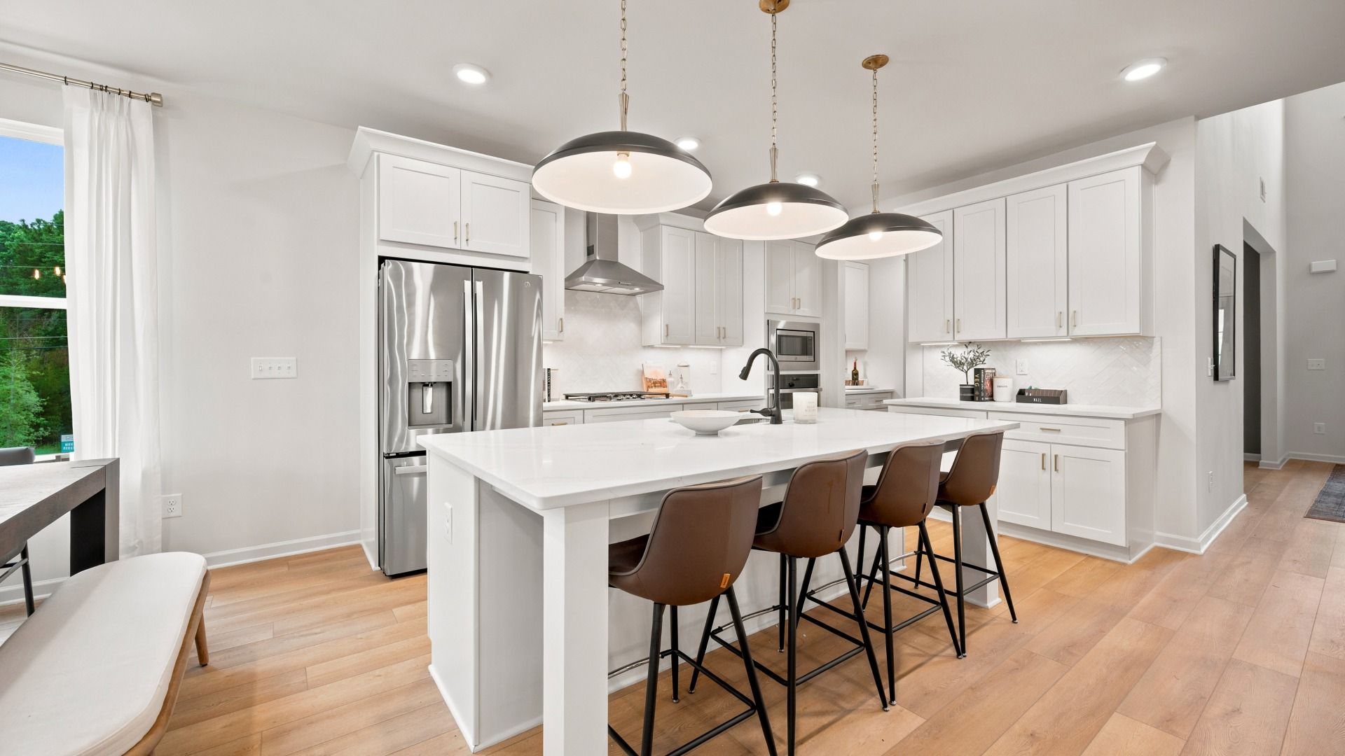 Rosemary II gourmet kitchen with modern tile backsplash, white cabinetry, and large island with pendant lighting at Brighton.
