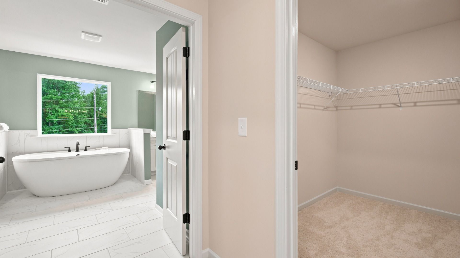 Primary walk-in closet connected to primary bath with carpet flooring and built-in shelving in the Rosemary II at Brighton.