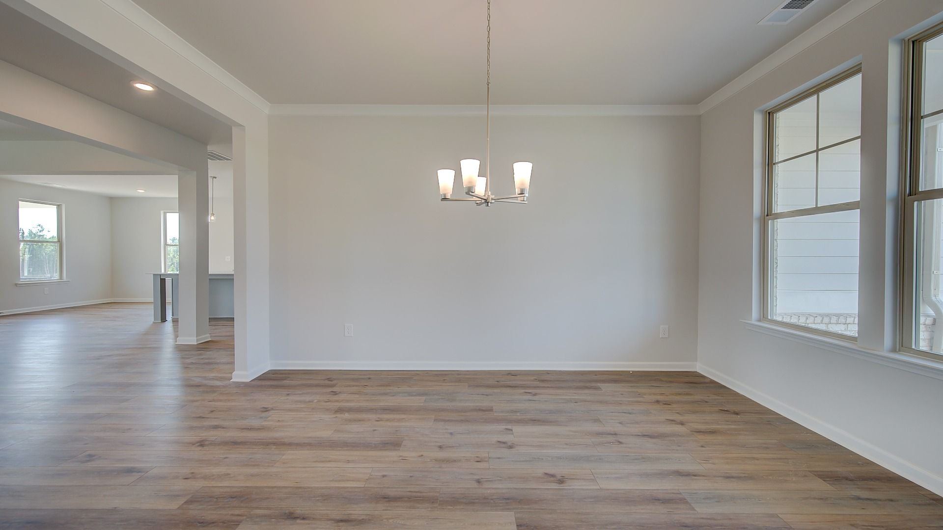 Open dining room with coffered ceiling and LVP flooring in the McKinley II at Brighton in Locust Grove, GA.